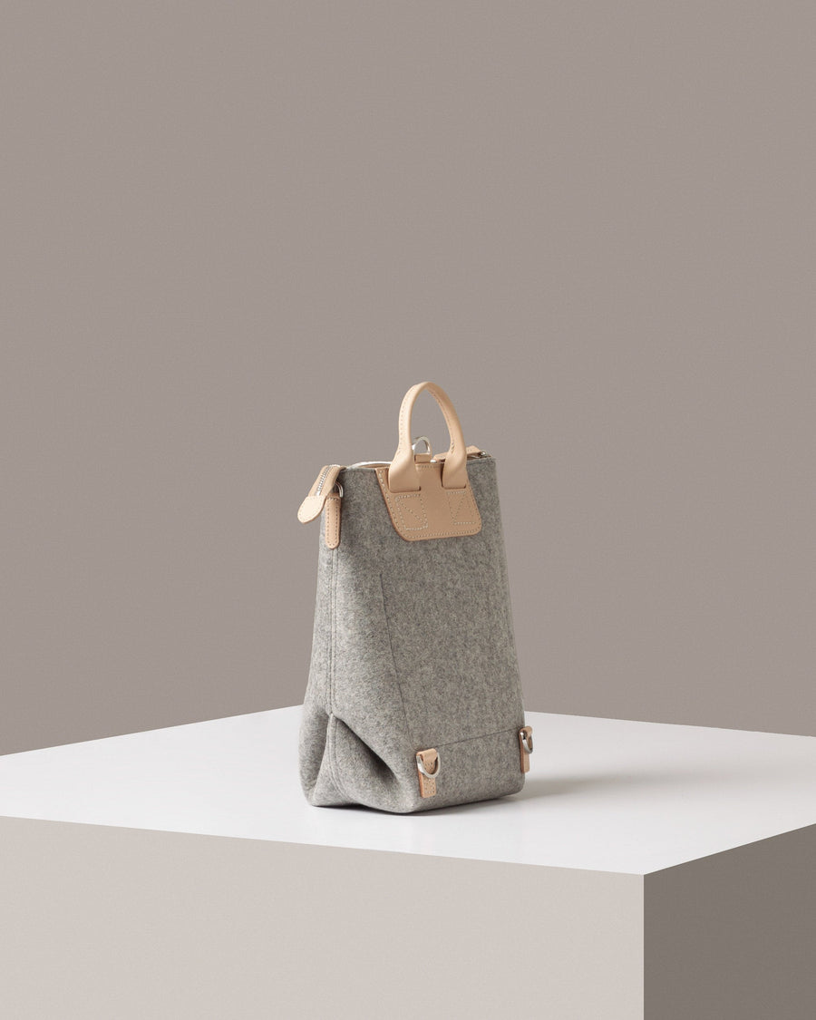 A light grey Bedford Merino Wool Felt Midi Backpack on a white base displayed in a side-view
