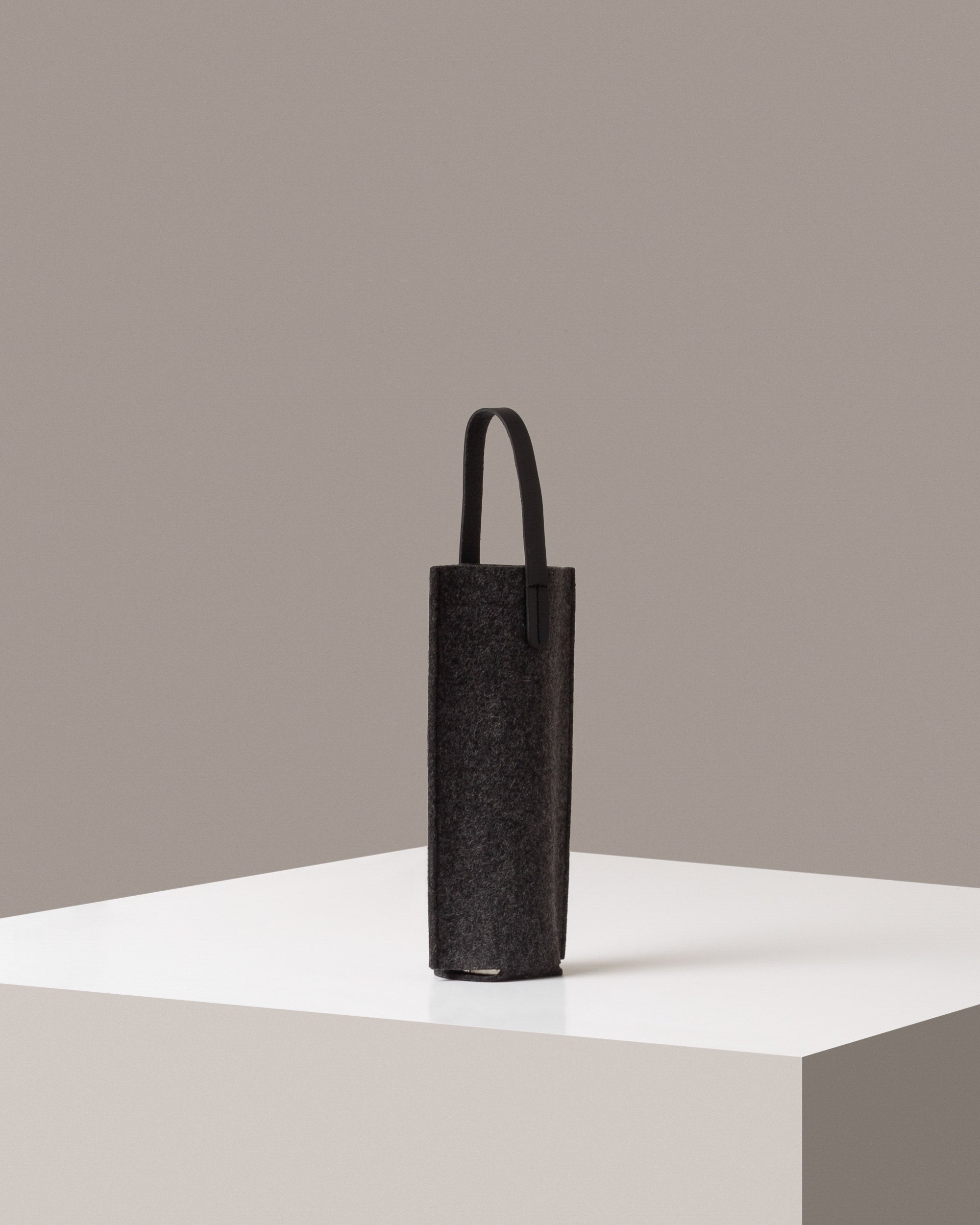 A dark grey Hana Merino Wool Bottle Bag on a white base displayed in a side-view

