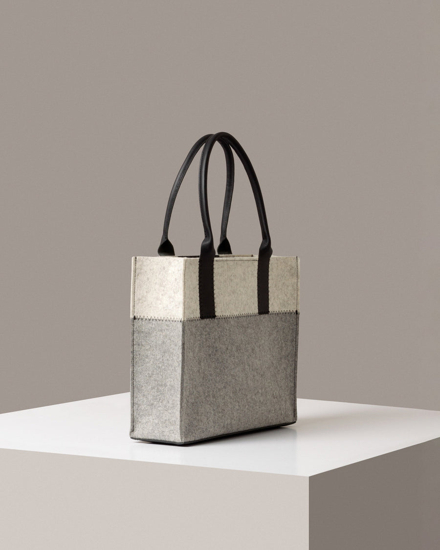 A Jaunt Midi Merino Wool Felt Tote by Graf Lantz in white, gray, and black colors on a white base displayed in a side-view
