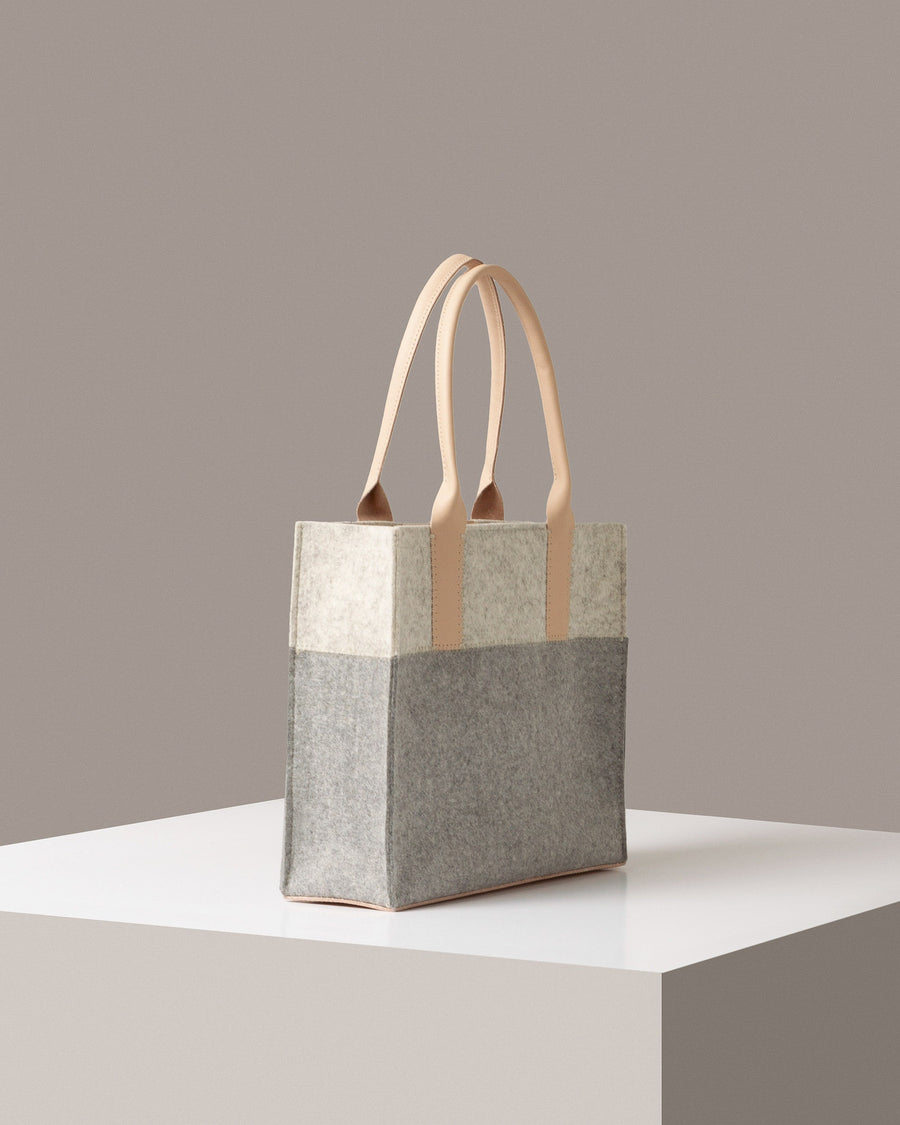 A Jaunt Midi Merino Wool Felt Tote in white, gray, and beige colors on a white base displayed in a side-view
