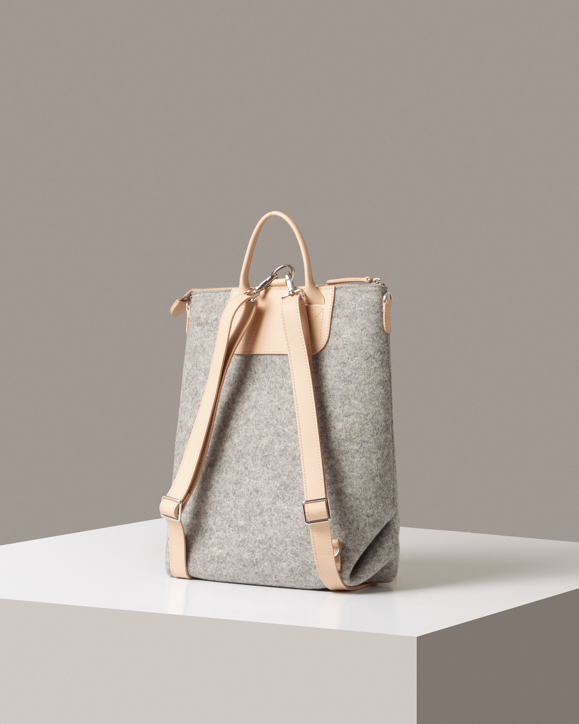 Rear view of a granite-colored Bedford Merino Wool Felt Backpack by Graf Lantz featuring beige leather shoulder straps