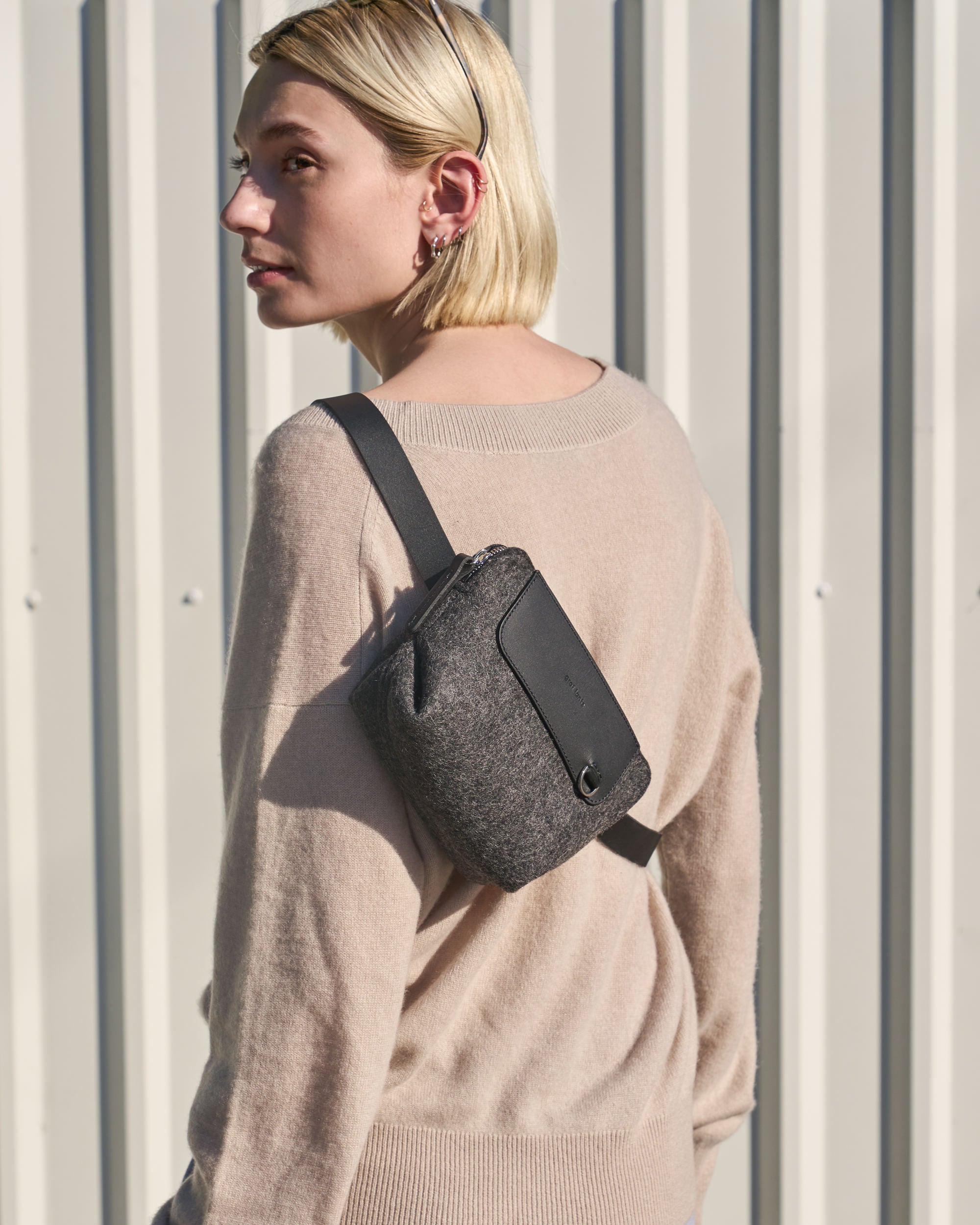 A dark grey Bedford Merino Wool Felt Belt Bag worn as a crossbody by a woman