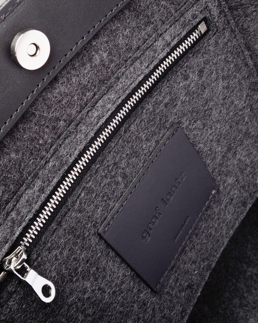 Interior view of a gray Frankie Merino Wool Felt Midi tote bag featuring a zippered felt pocket, black leather trim, and nickel hardware, highlighted in detail