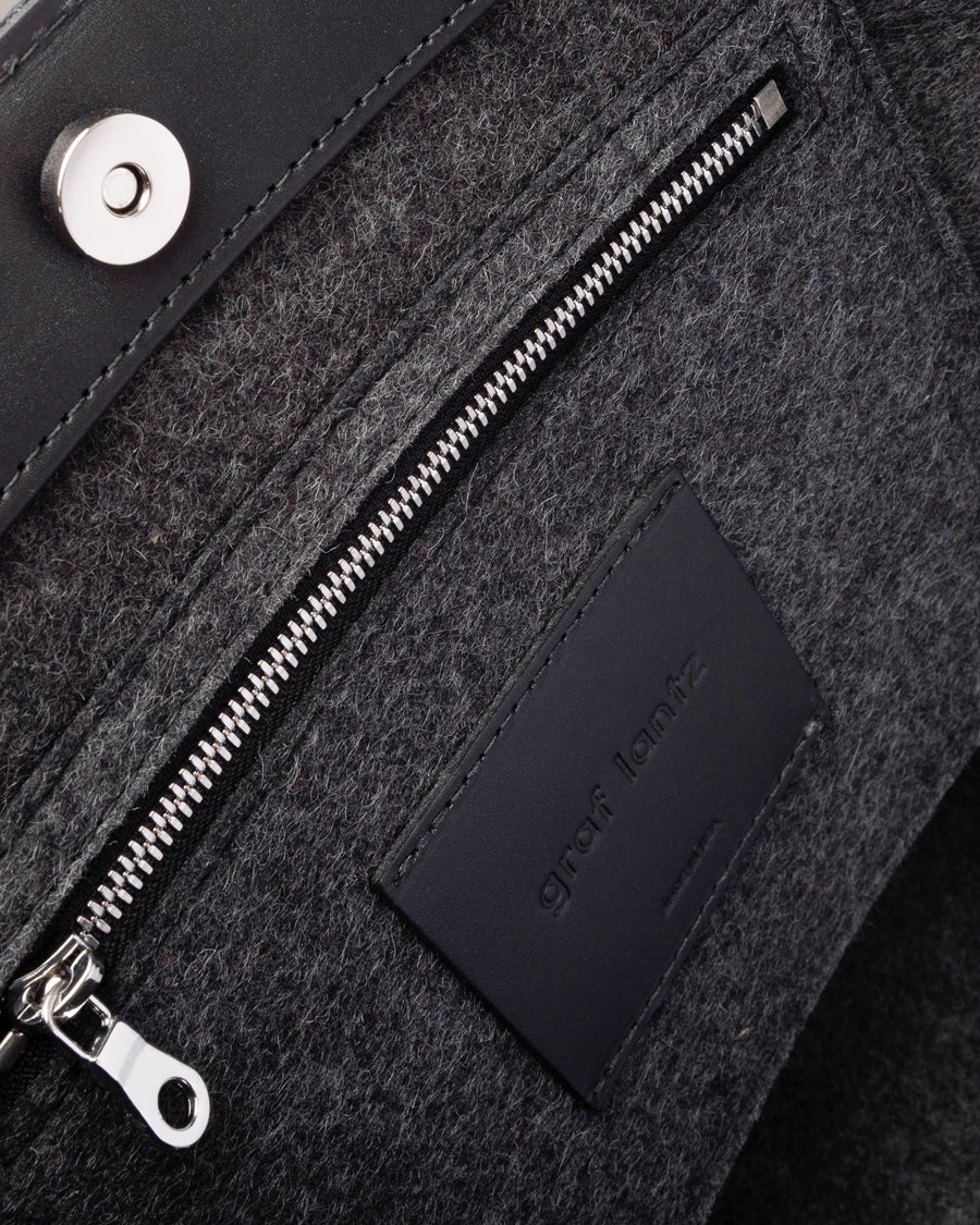 Interior view of Frankie Merino Wool Felt Tote featuring a zippered felt pocket, black leather trim, and nickel hardware, highlighted in detail
