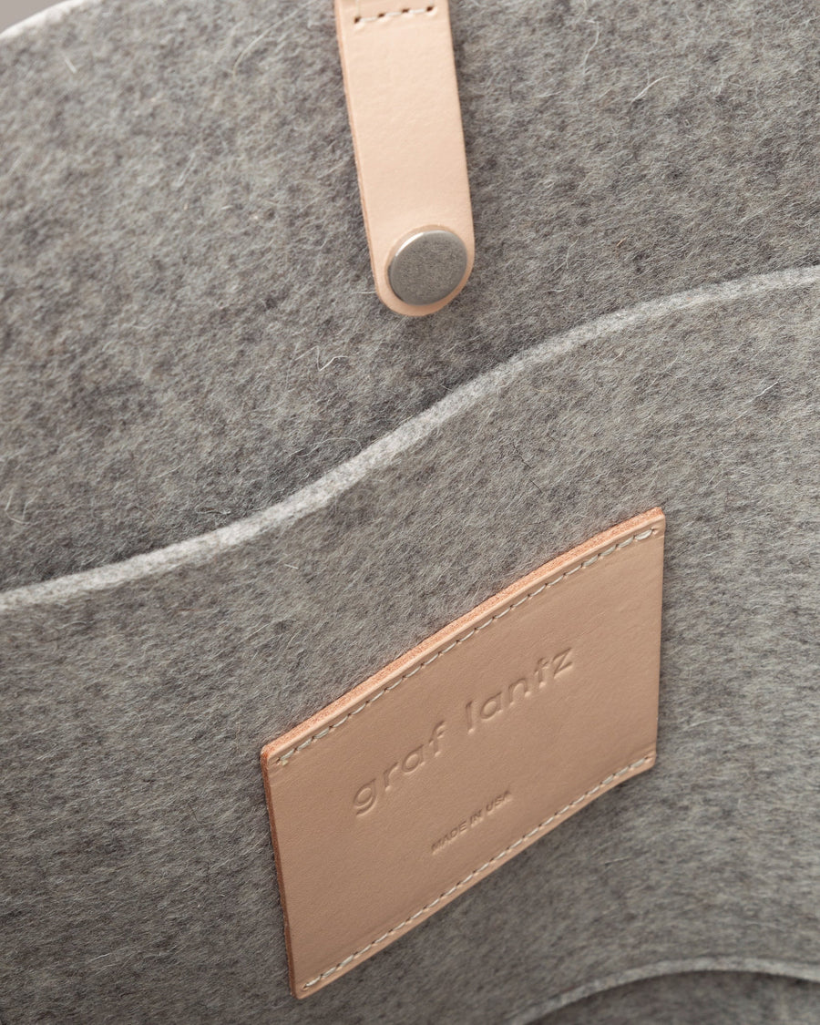 Interior view of a grey Hana Merino Wool Felt Boat bag featuring a felt pocket, snap closure, and vachetta leather, highlighted in detail