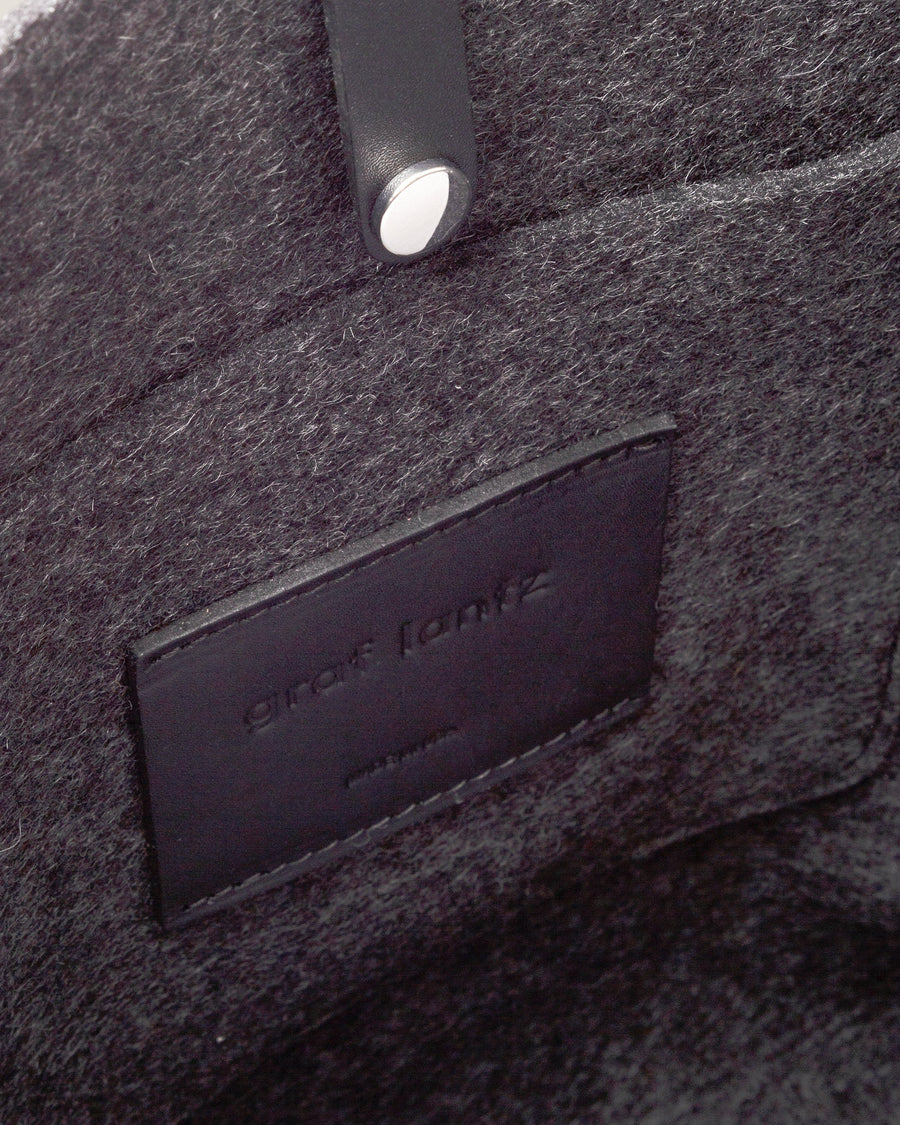 Interior view of a grey Hana Merino Wool Felt Tote bag featuring an interior patch pocket, and a snap closure, highlighted in detail
