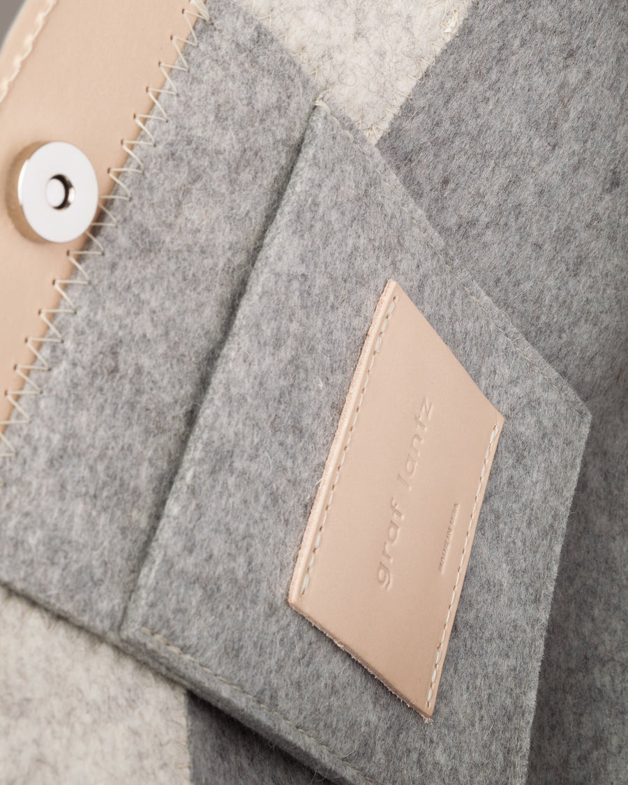 Interior view of a gray Jaunt Midi Merino Wool Felt Tote bag featuring a felt pocket, beige leather trim, and a magnetic snap closure, highlighted in detail