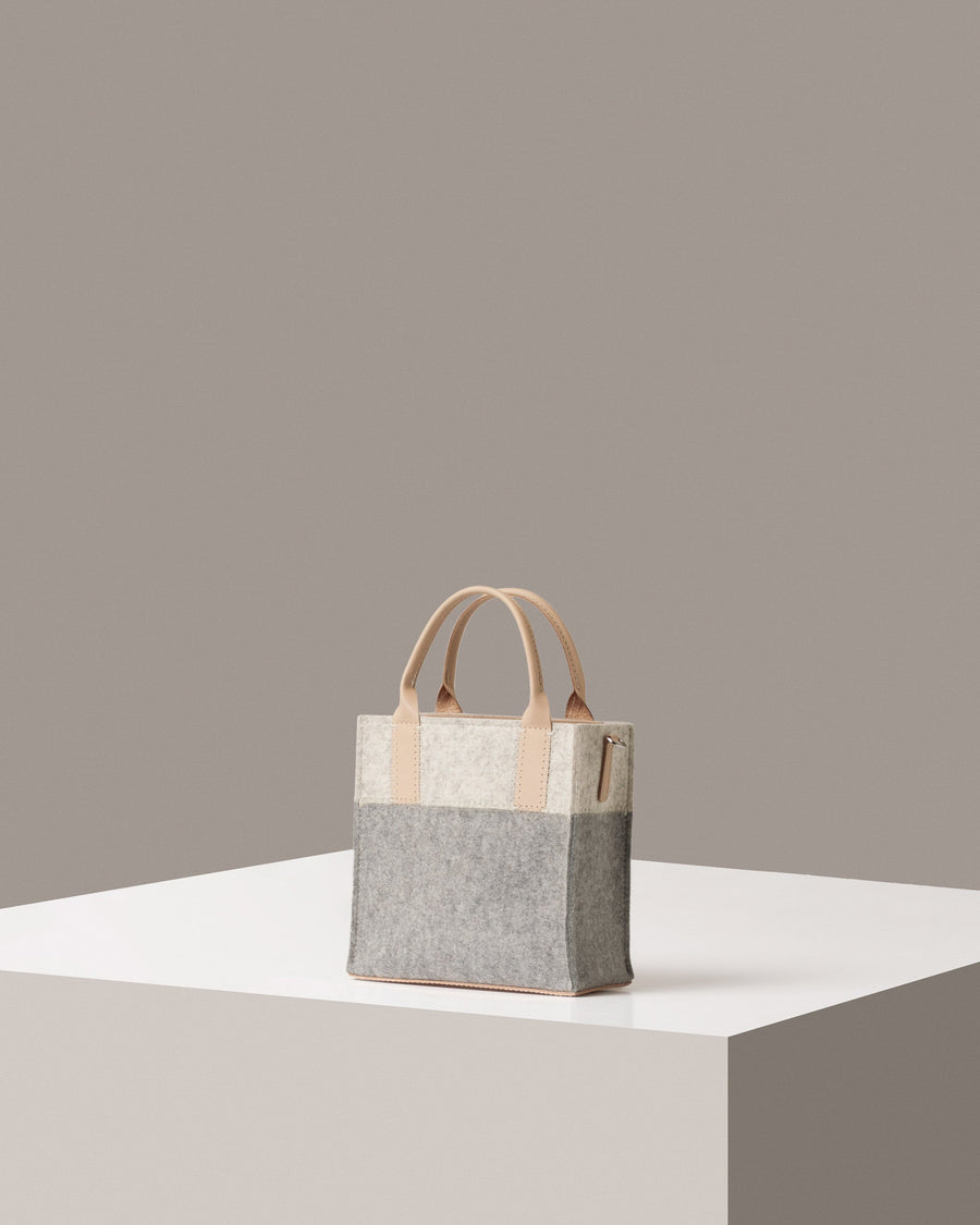 Rear view of a grey, white and beige Jaunt Mini Merino Wool Felt Tote bag by Graf Lantz featuring beige leather accents 