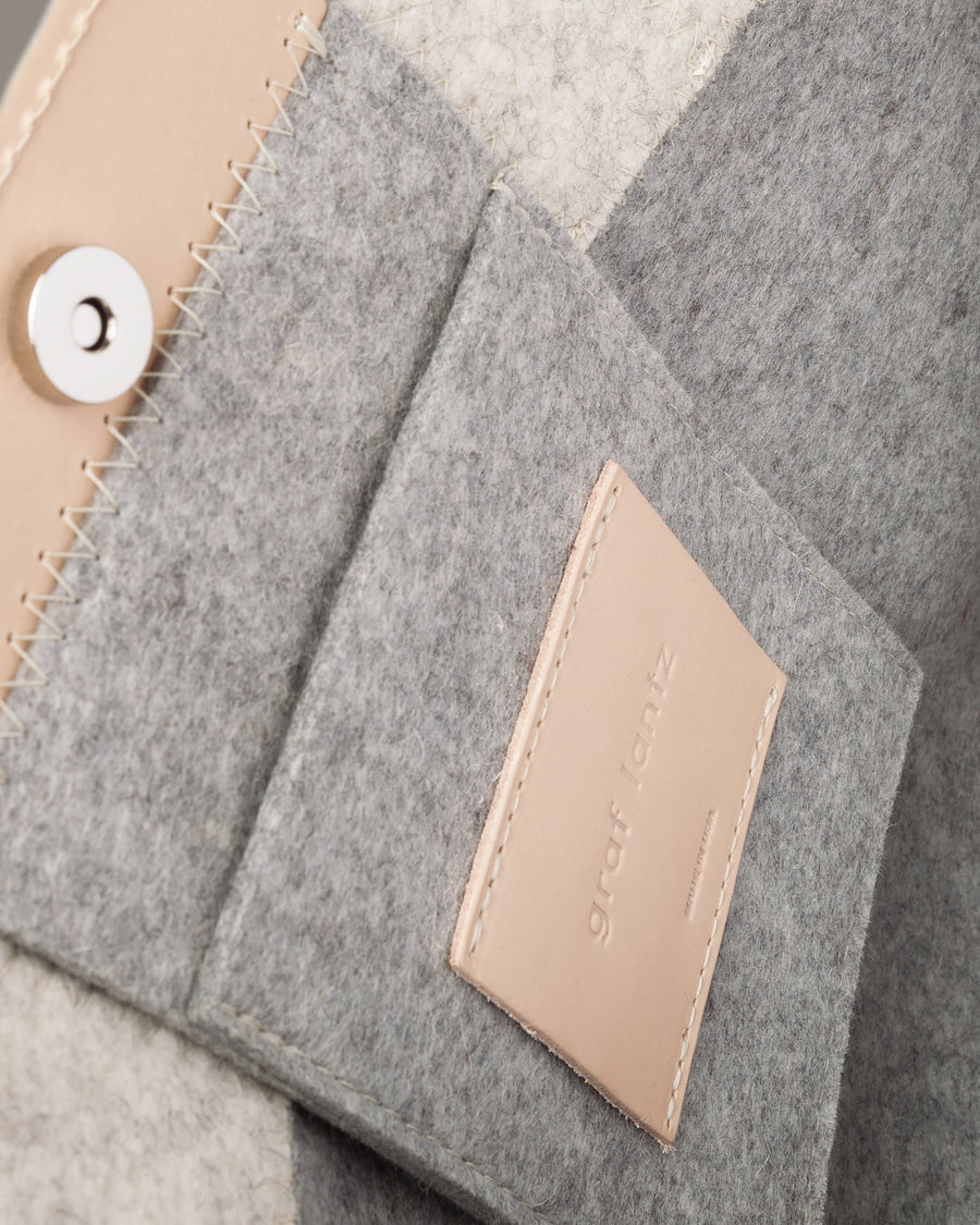 Interior view of a gray Jaunt Merino Wool Felt Tote featuring a felt pocket, beige leather trim, and a magnetic snap closure, highlighted in detail