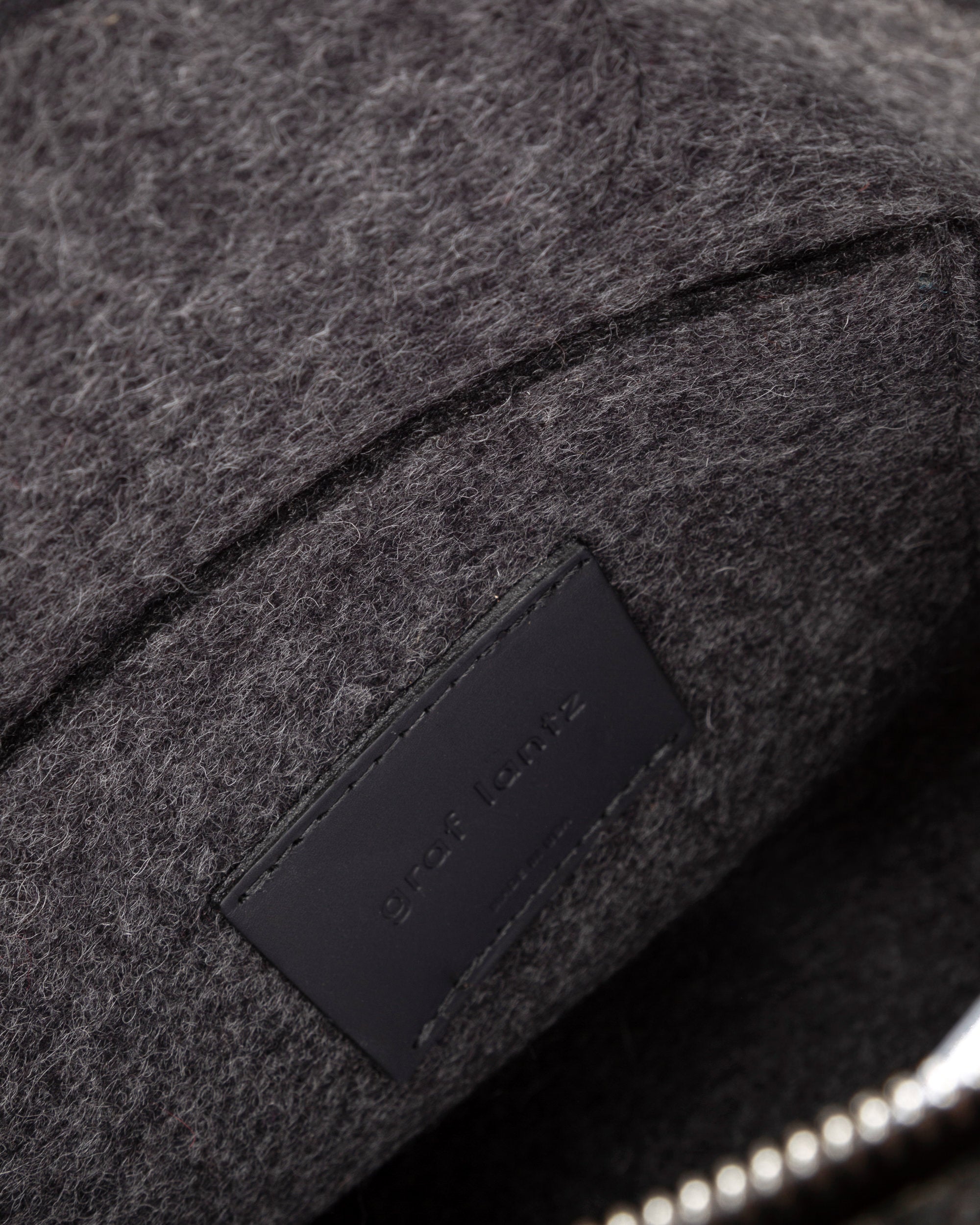Interior view of a grey Bedford Merino Wool Felt Backpack featuring a zip-top closure and interior patch pocket, highlighted in detail
