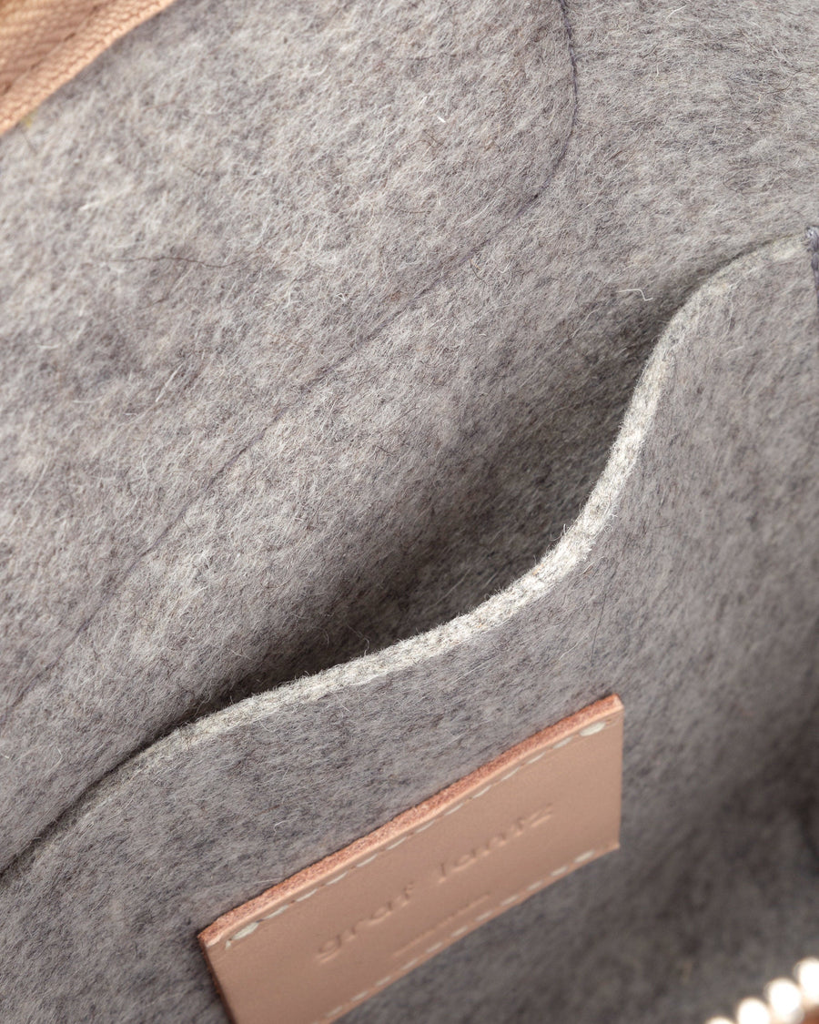 Interior view of a grey Bedford Merino Wool Felt Midi Backpack featuring an interior patch pocket and beige leather accents, highlighted in detail