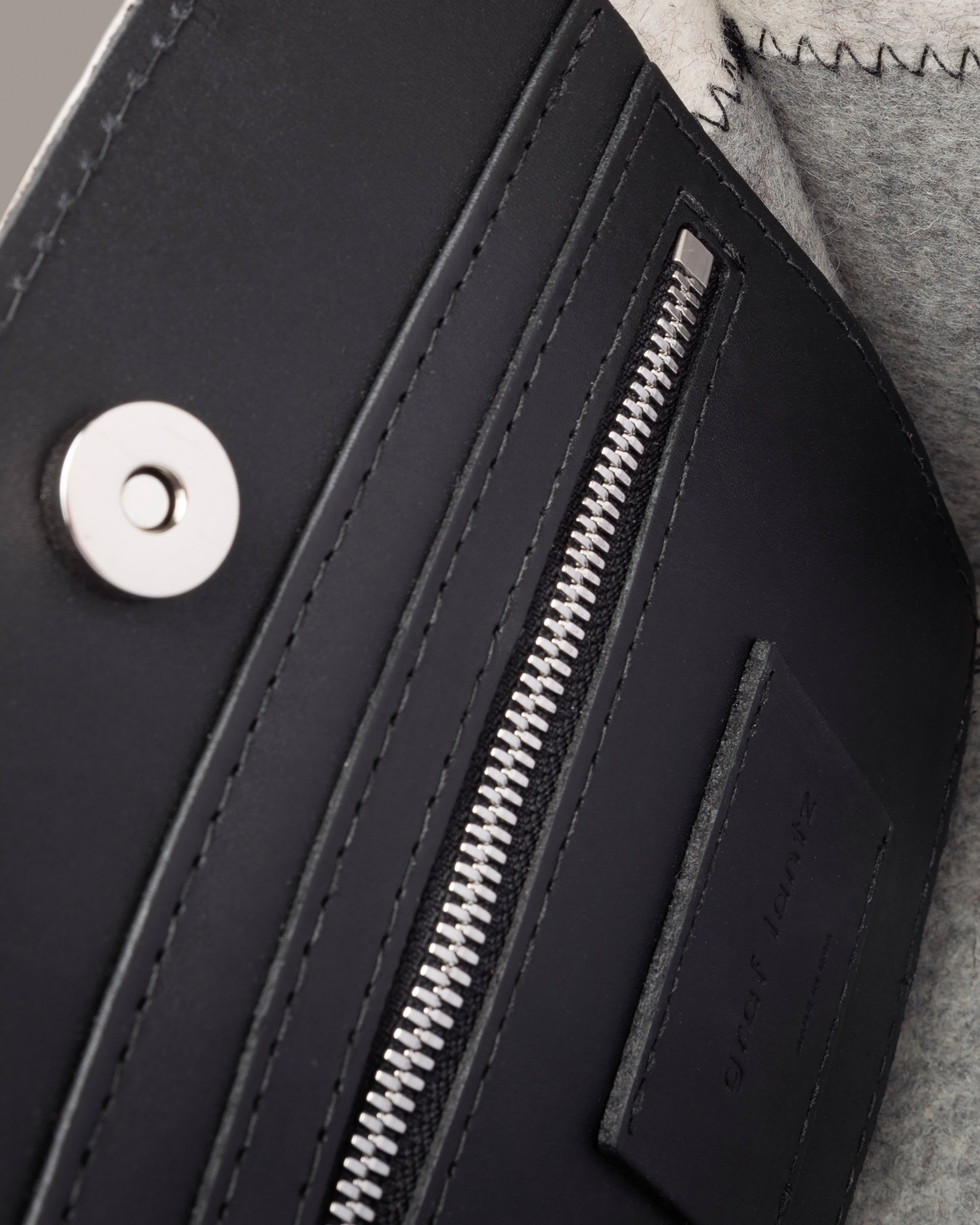 Interior view of a gray Jaunt Mini Merino Wool Felt Tote featuring a zippered leather pocket, a magnetic top closure, and nickel hardware, highlighted in detail