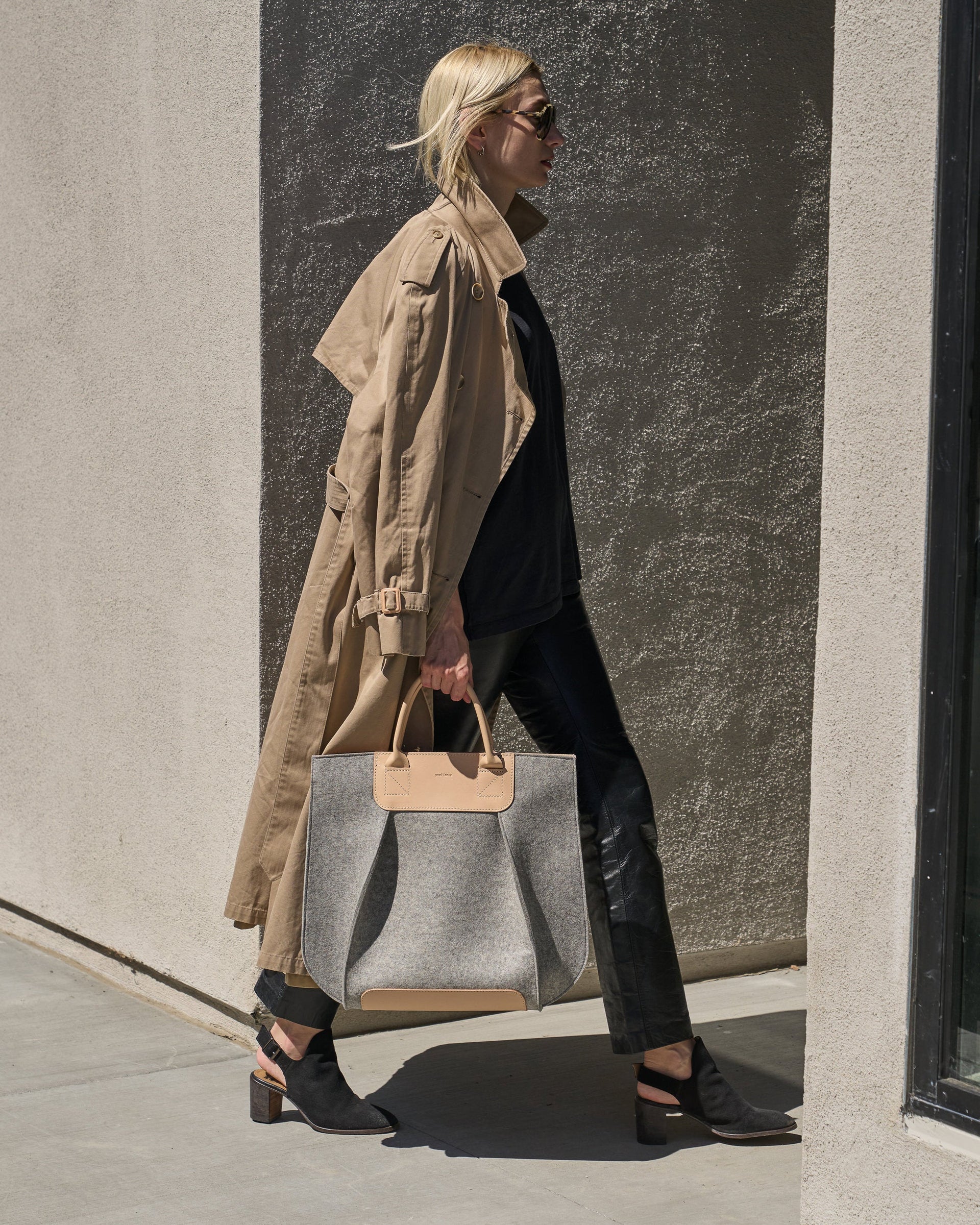 A Frankie Merino Wool Felt Tote carried by a woman, showcasing its handle-lengths and beige and grey colors