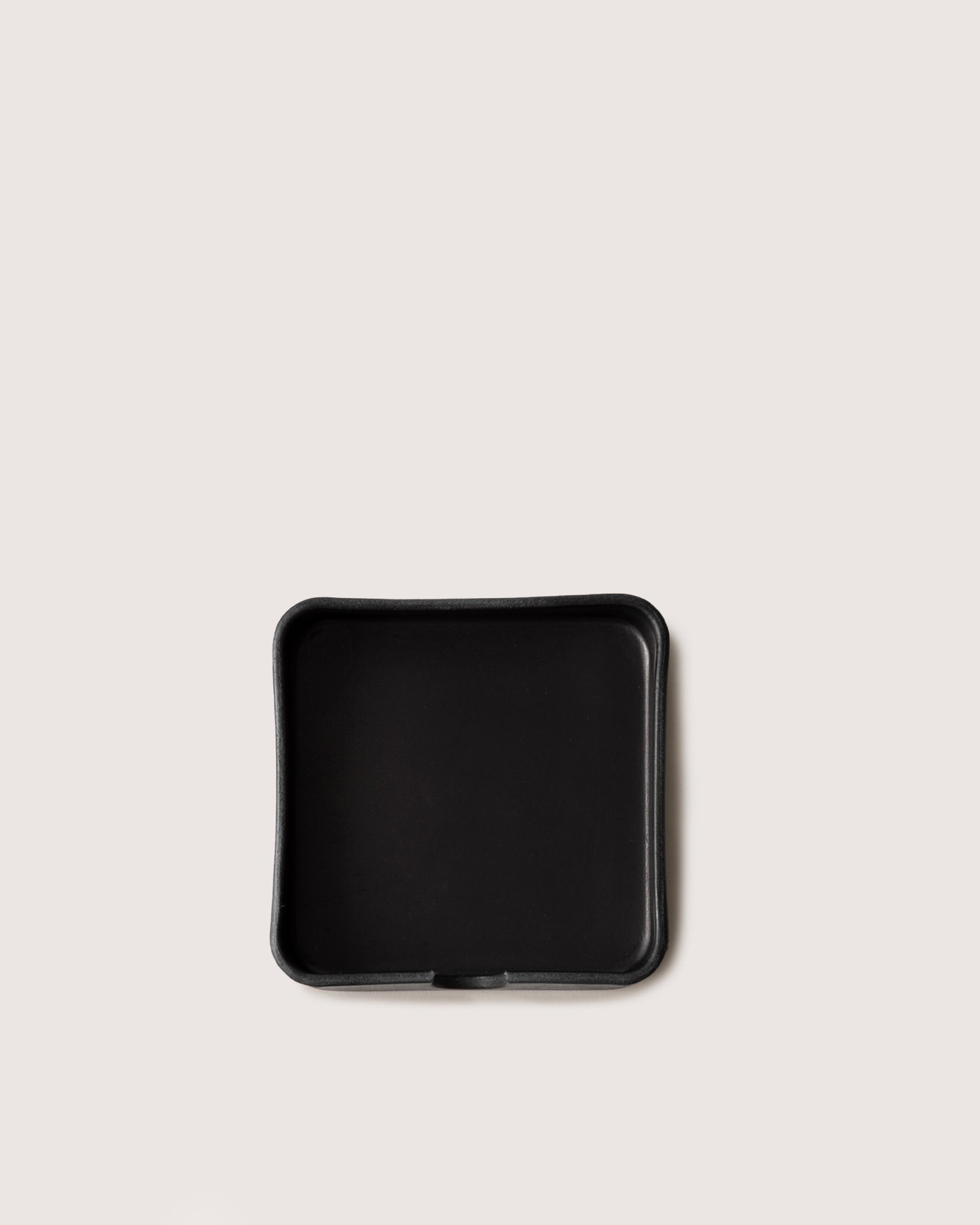 A sophisticated, empty black tray by graf lantz, featuring a square shape with slightly raised edges like an elegant organizer, is centered on a plain white background.