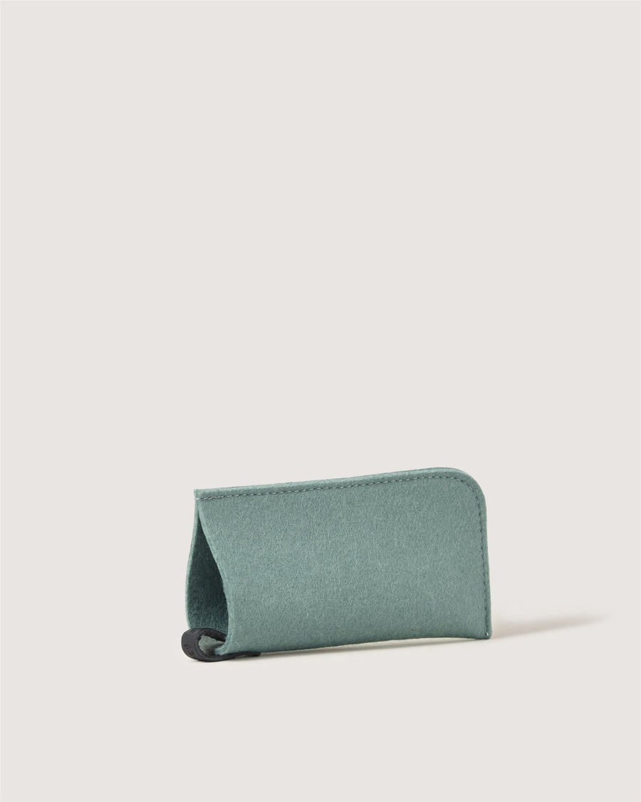 A small, soft, rectangular teal case by Graf Lantz with rounded edges stands upright on a light background. The case appears empty and has a partially open end.