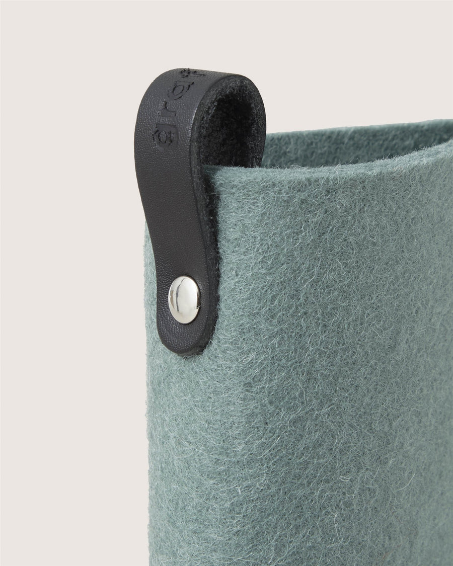 Close-up of a textured, light teal felt Graf Lantz container featuring a black leather loop embossed with the number 15 and fastened by a silver rivet at the top edge.