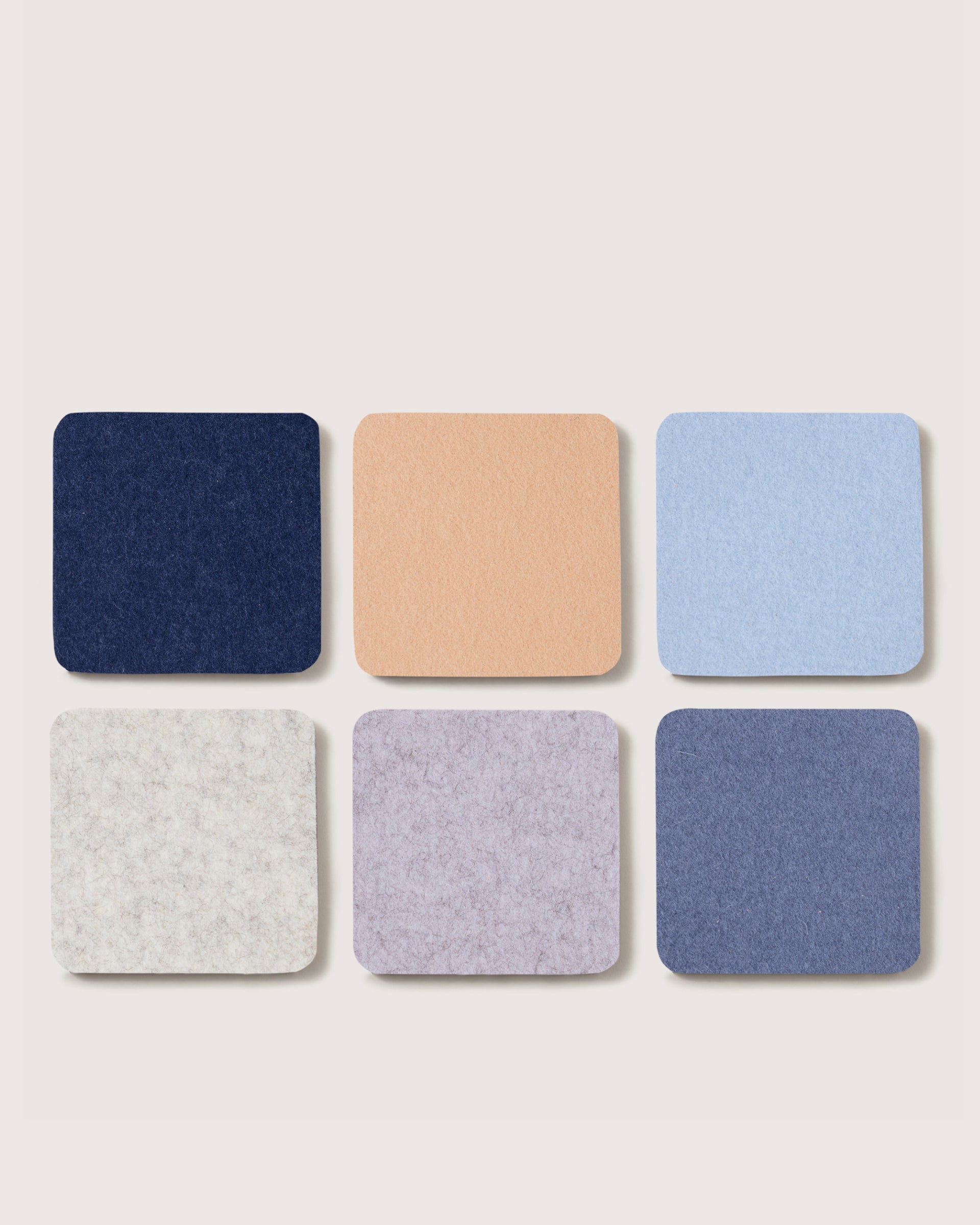 Set of six square coasters in different colors on a light gray background