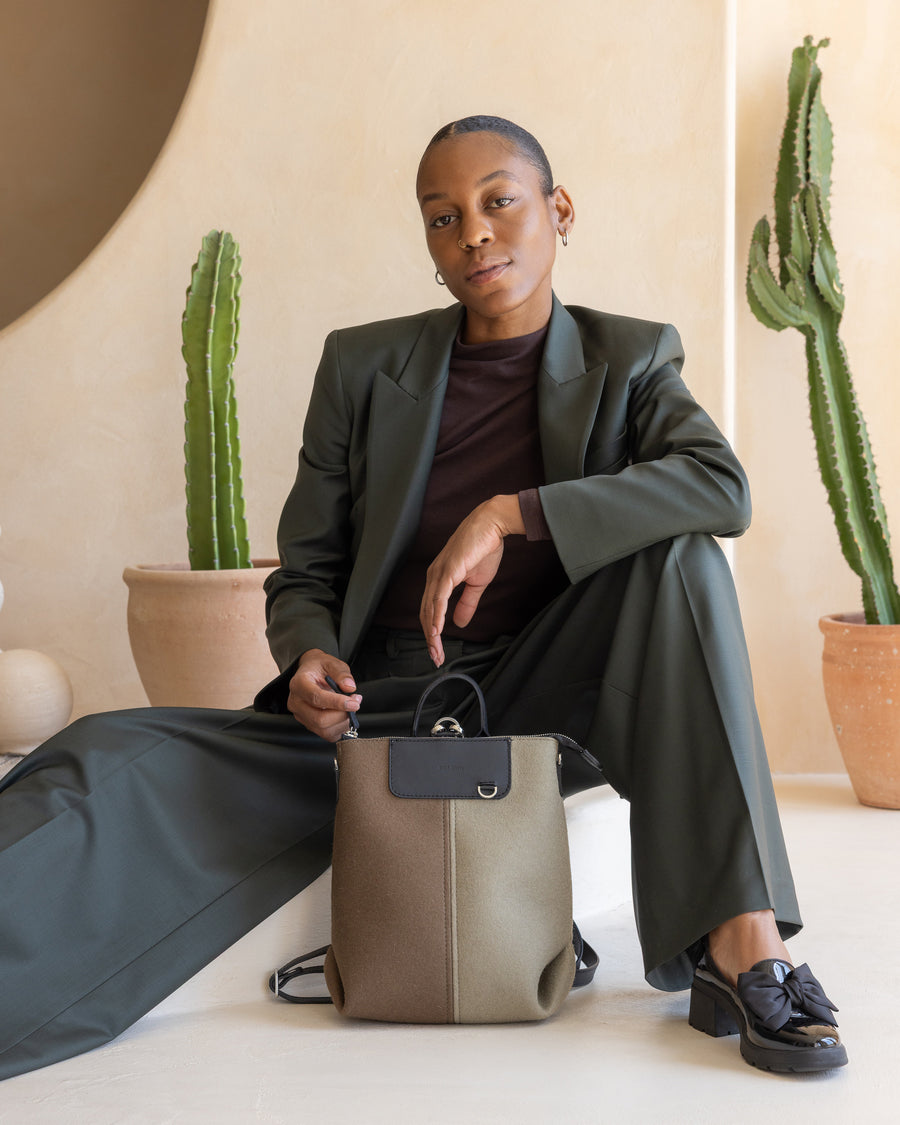 Person holding a Cumin & Clay colorblock midibackpack with cacti in the background