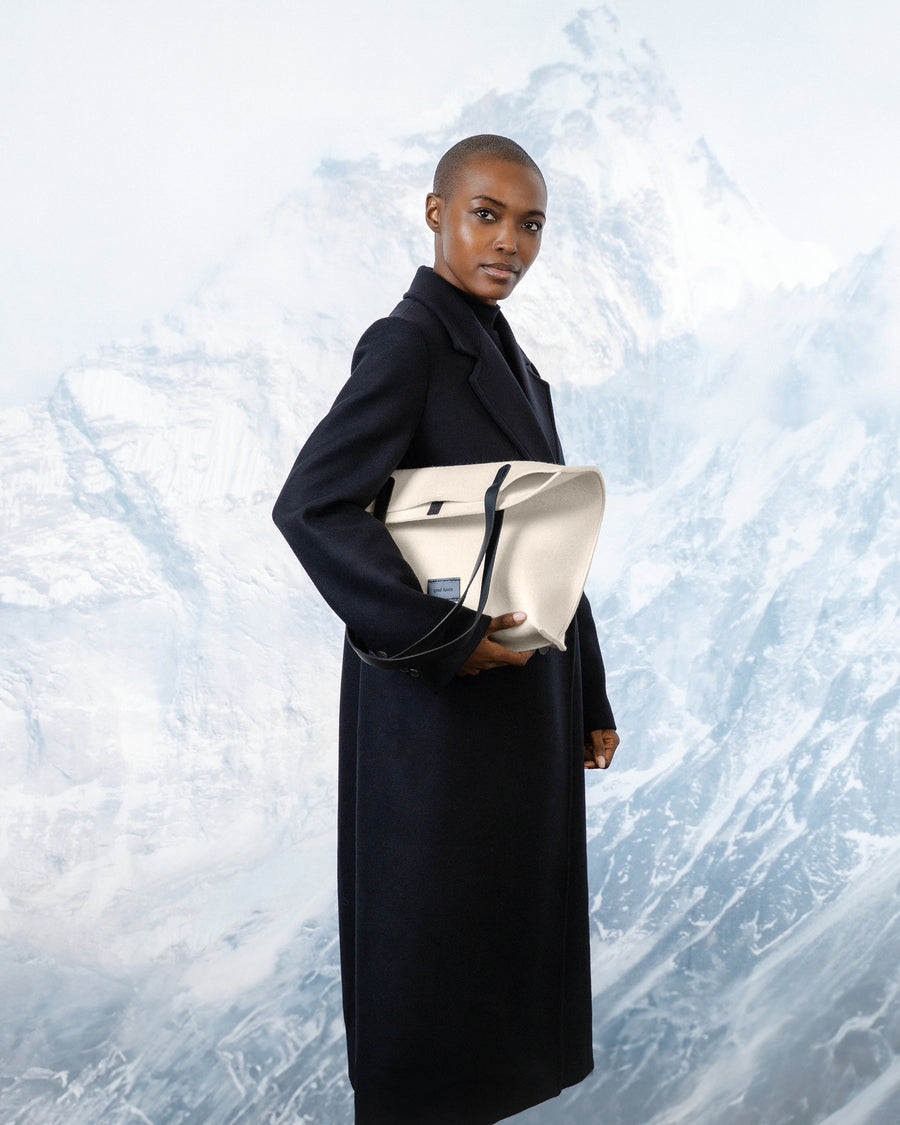 Person holding a White Merino wool felt bag against a snowy landscape