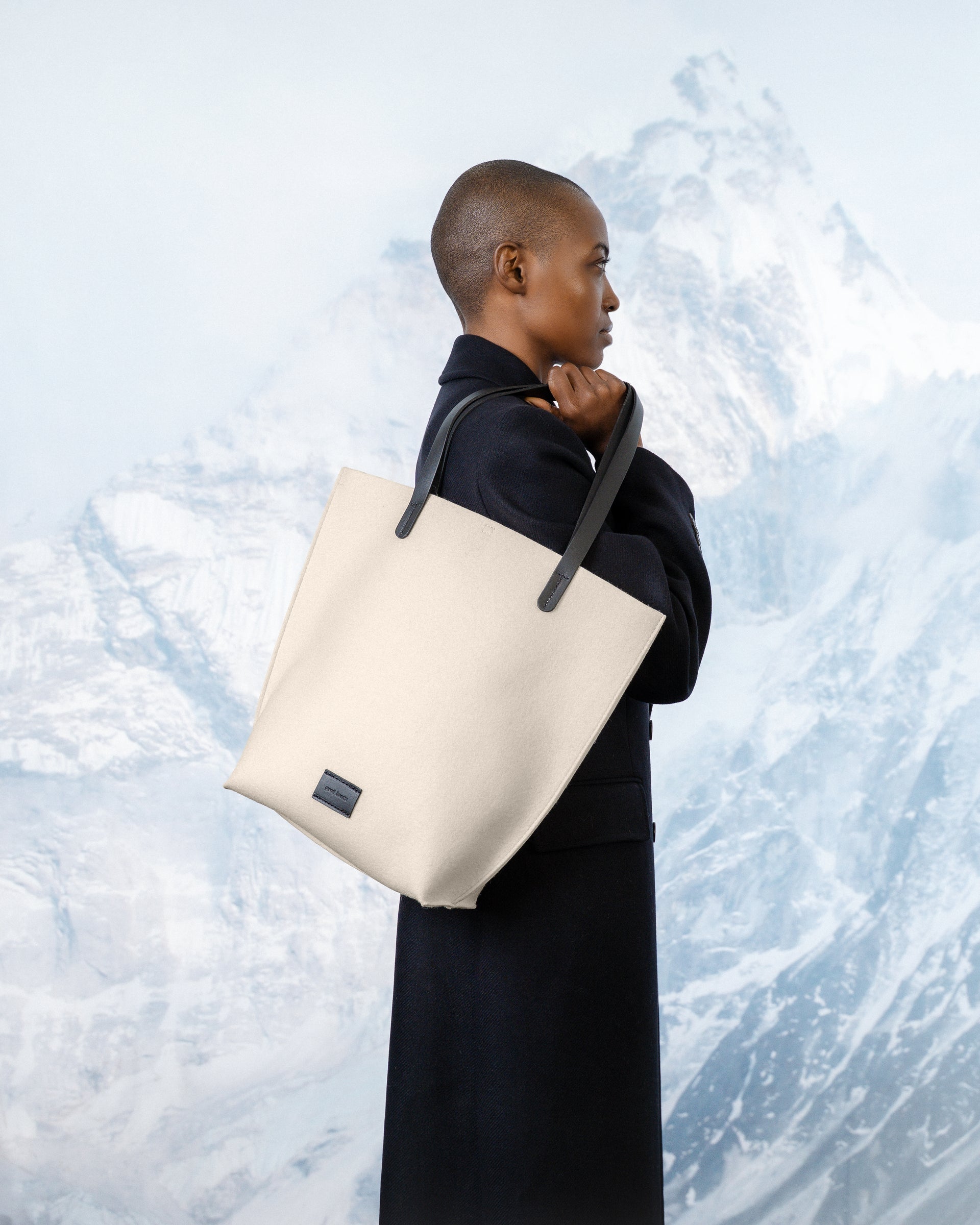 Person holding a White Merino wool felt tote bag against a snowy mountain background