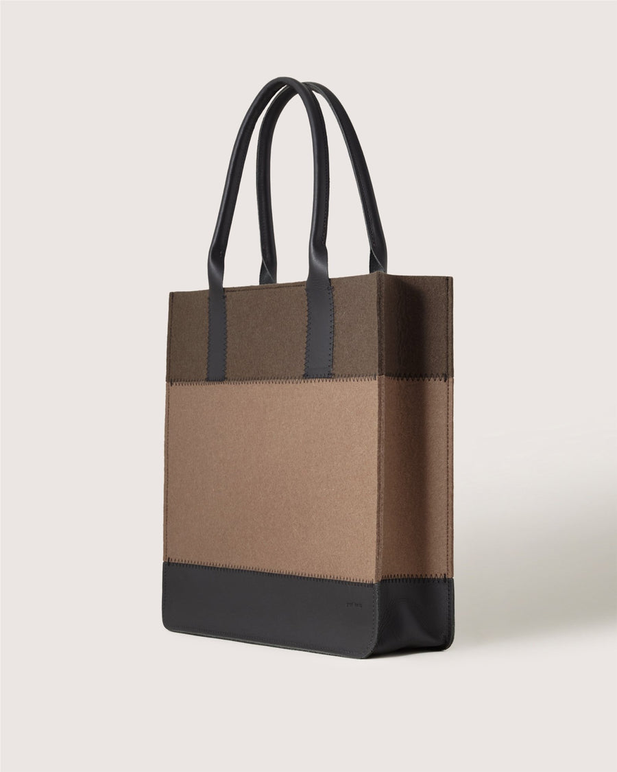 A Graf Lantz rectangular tote bag with black handles, brown upper panels, tan lower panels, and a black base is displayed against a plain light background.