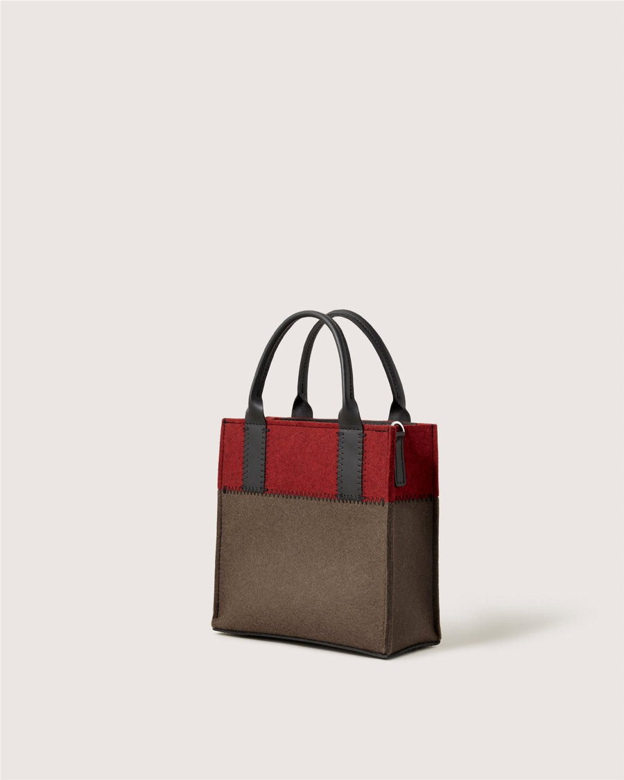 The Graf Lantz handbag features a small, rectangular shape with black handles, a brown body, and a wide red band at the top, set against a plain light background.