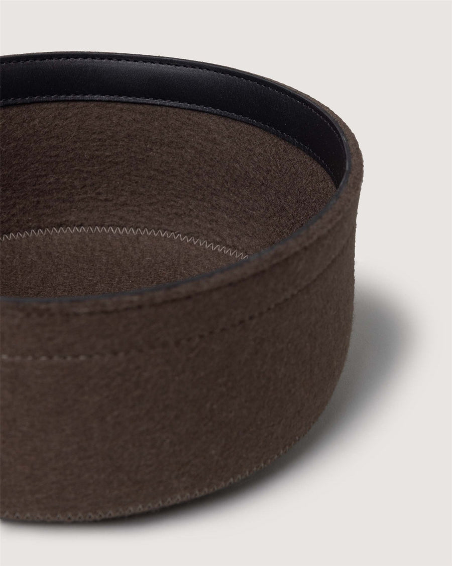 A close-up of a round, brown felt storage basket by Graf Lantz, featuring stitched details and a black inner lining, set against a plain light background.