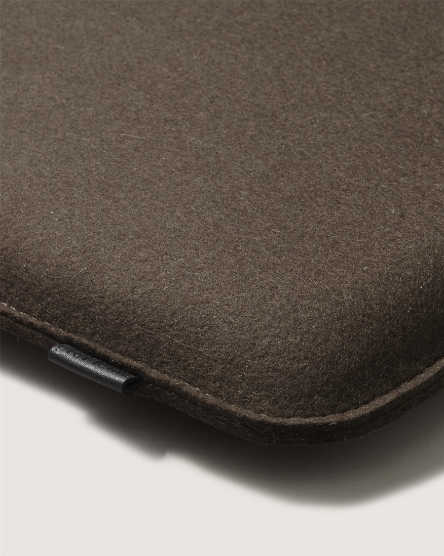 Close-up of a Graf Lantz brown felt-textured rectangular object, likely a laptop sleeve or case, featuring rounded edges and a small black pull tab on the side against a light background.