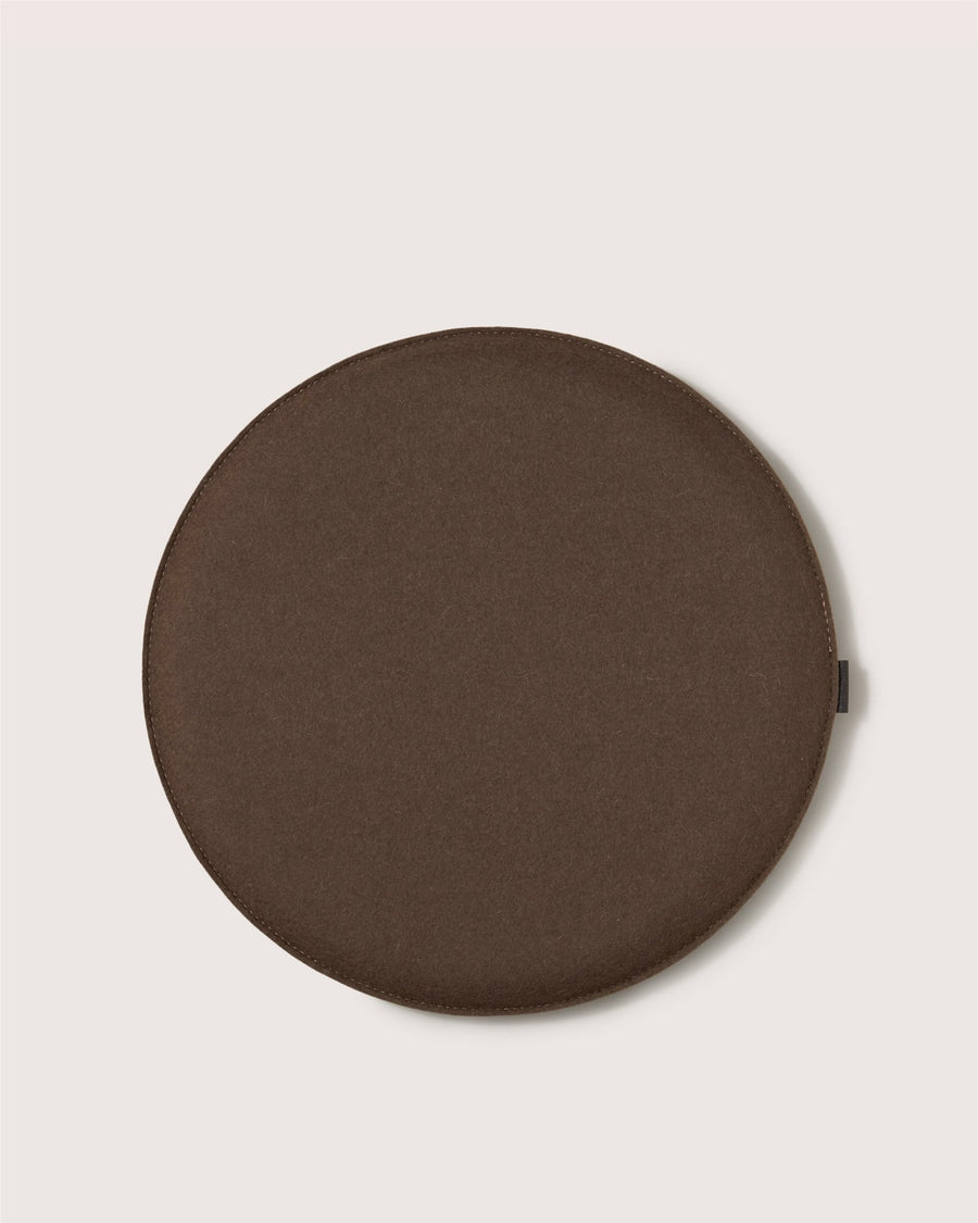 A round, flat brown cushion by Graf Lantz with smooth edges, shown on a light background.