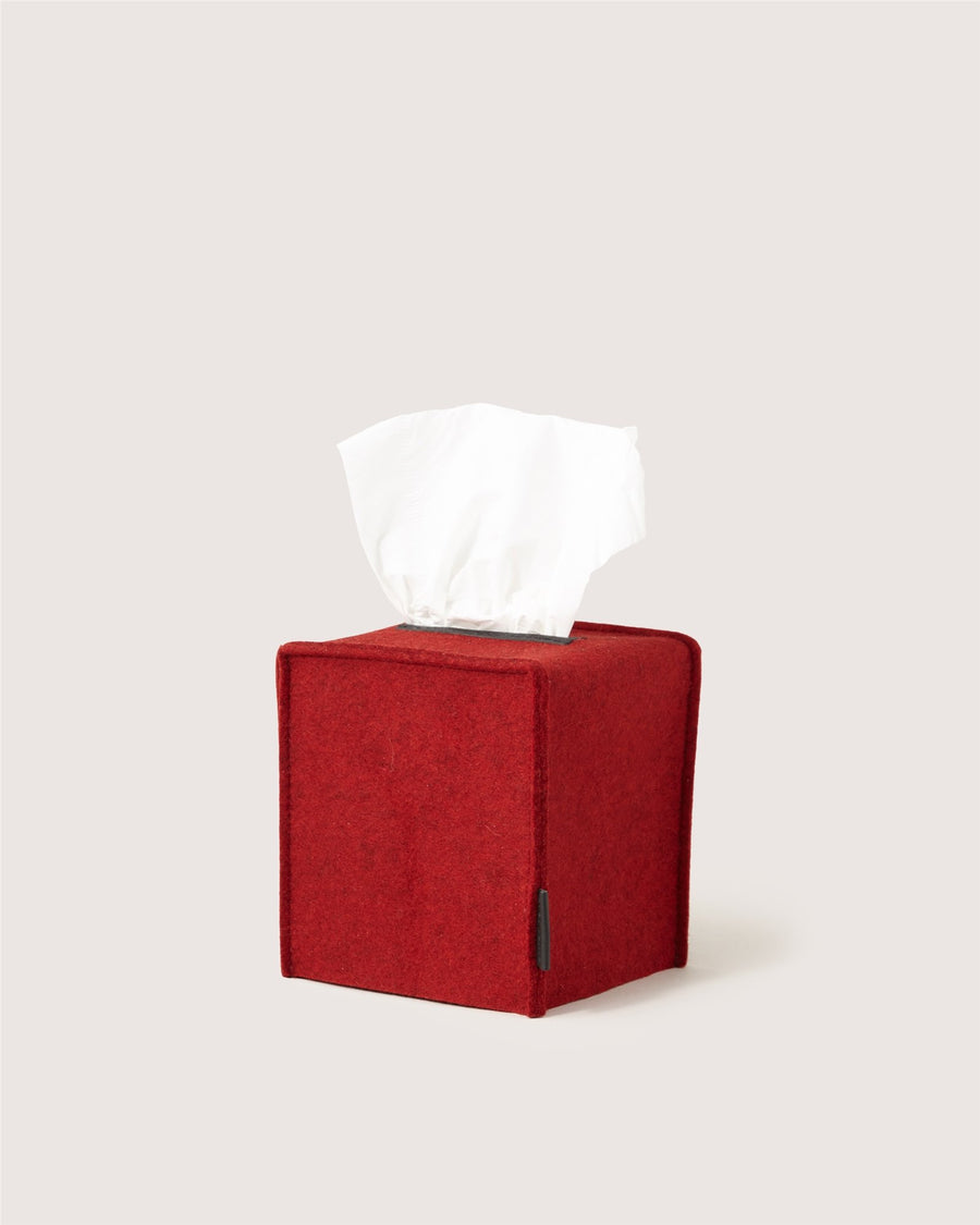 A red Graf Lantz fabric cube tissue box holder with a white tissue protruding from the top, set against a plain light background.