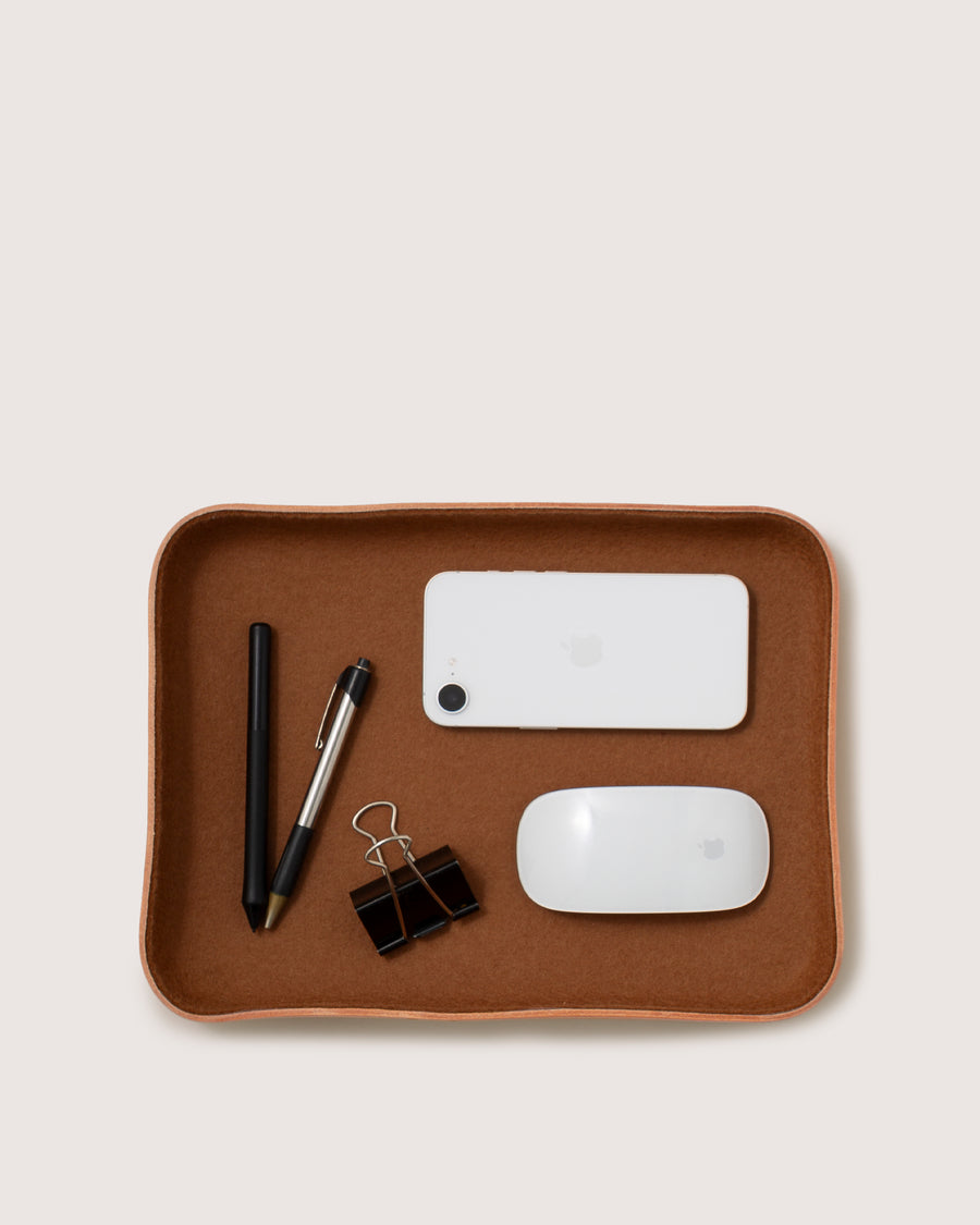 A graf lantz Kawabon Tray neatly holds a black pen, a two-toned pen, two black binder clips, a white smartphone, and a white computer mouse on a light background.