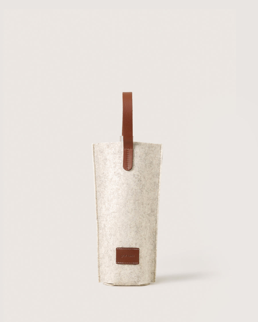 A Merino Wool Felt Single Wine Carrier in color Heather White Sienna with a brown leather handle, white background