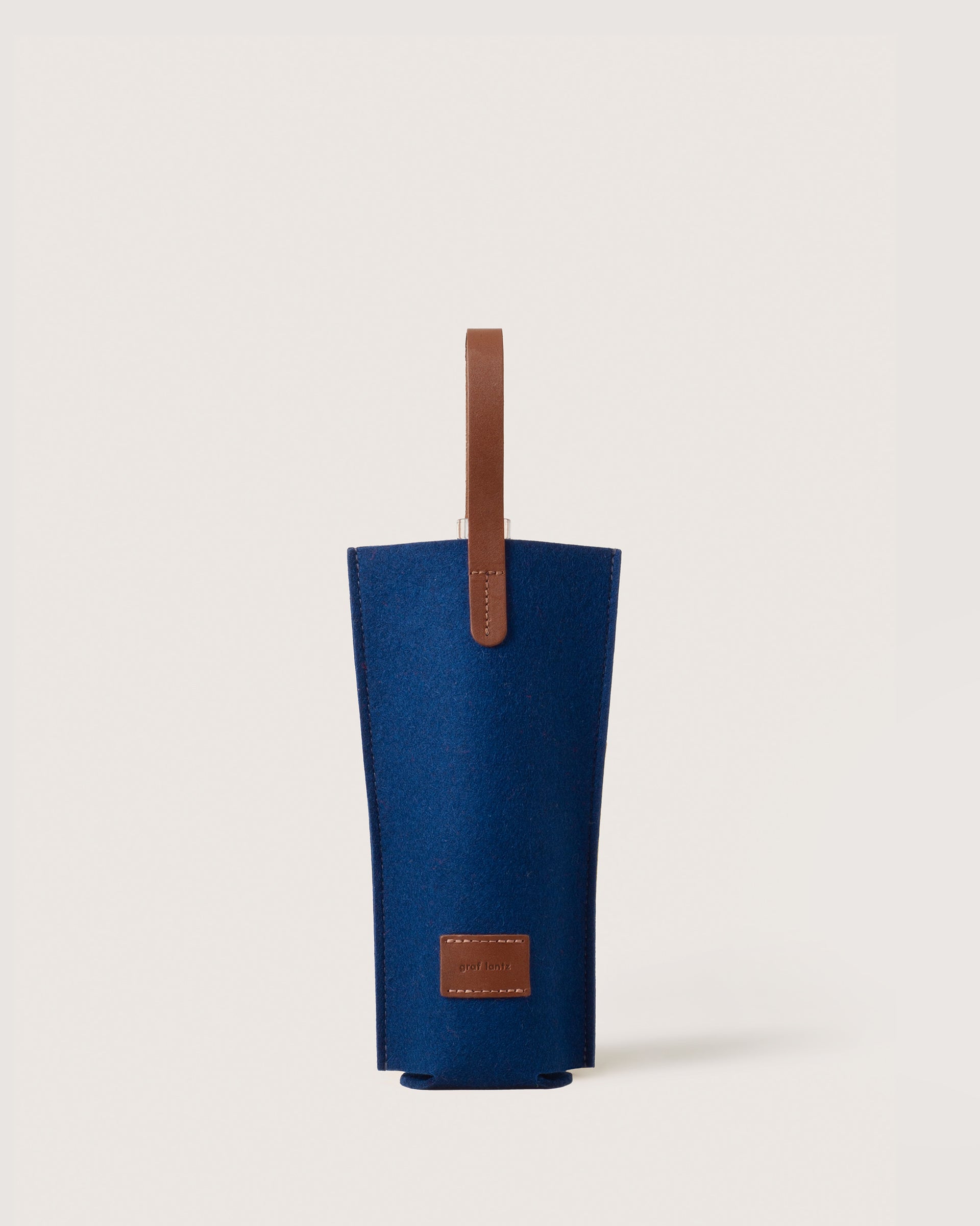 A Merino Wool Felt Single Wine Carrier in color Marine Sienna with a brown leather handle, white background