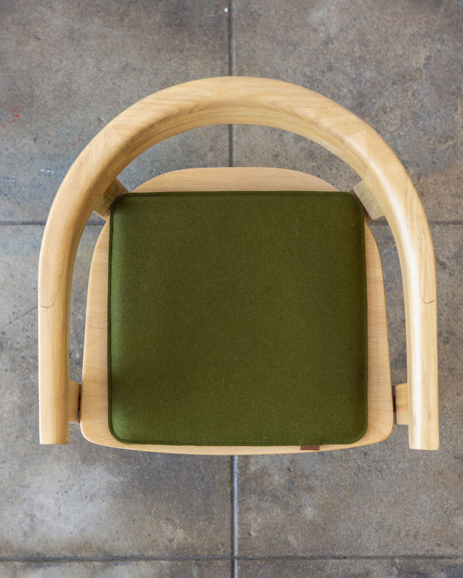 A square Zabuton Merino Wool Felt Seat Pad by Graf Lantz in Moss Sienna on a wooden chair, view from above