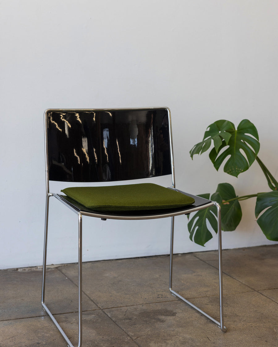 A green Zabuton Merino Wool Felt Square Seat Pad by Graf Lantz on a black chair, side view