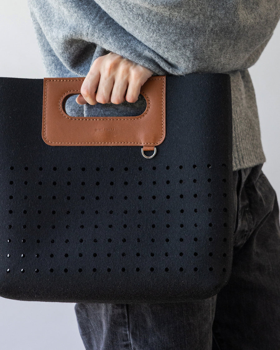 Close-up of black Asobi Merino Wool Midi held by woman in one hand