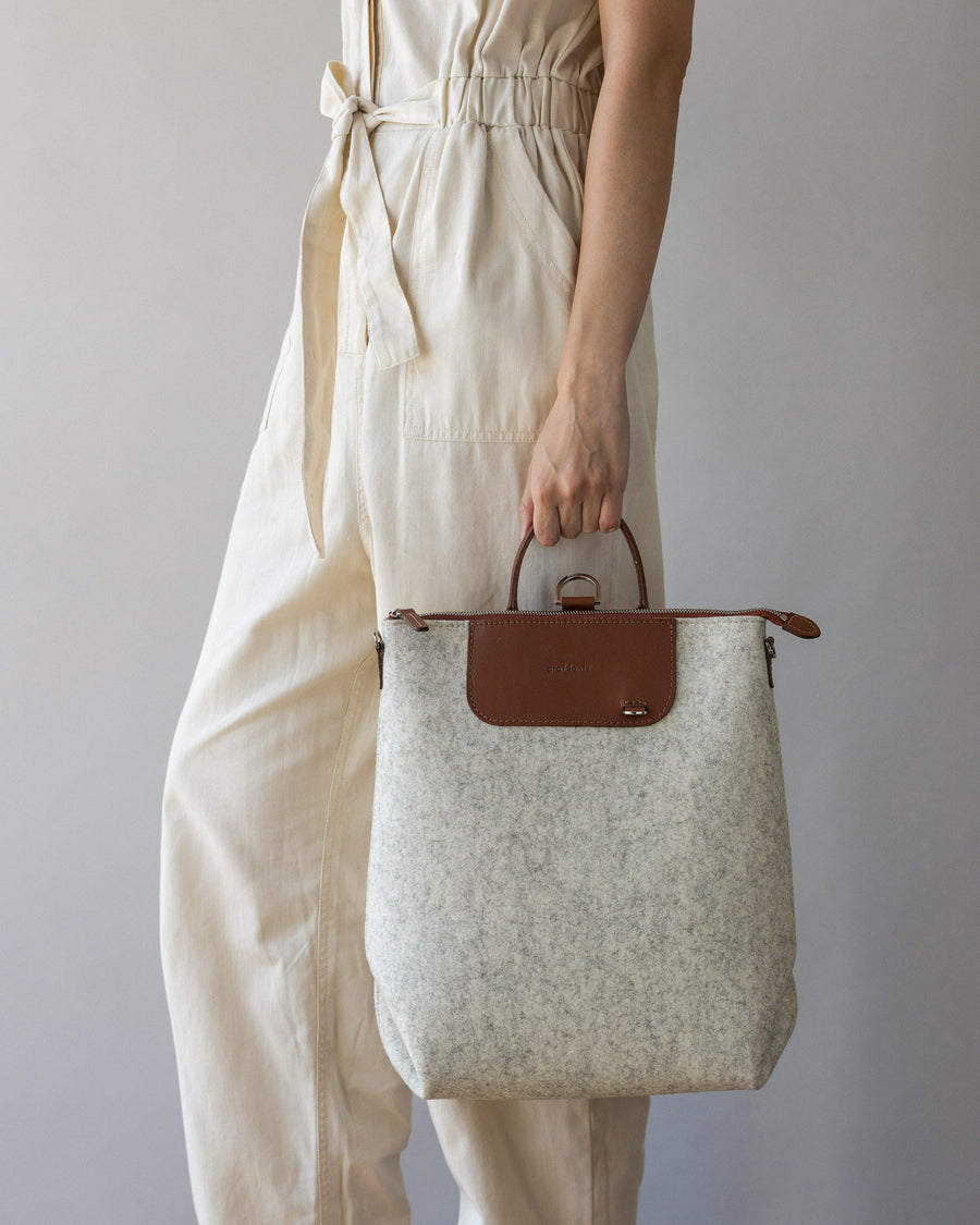 Woman with Heather White Bedford Merino Wool Backpack in one hand, side view