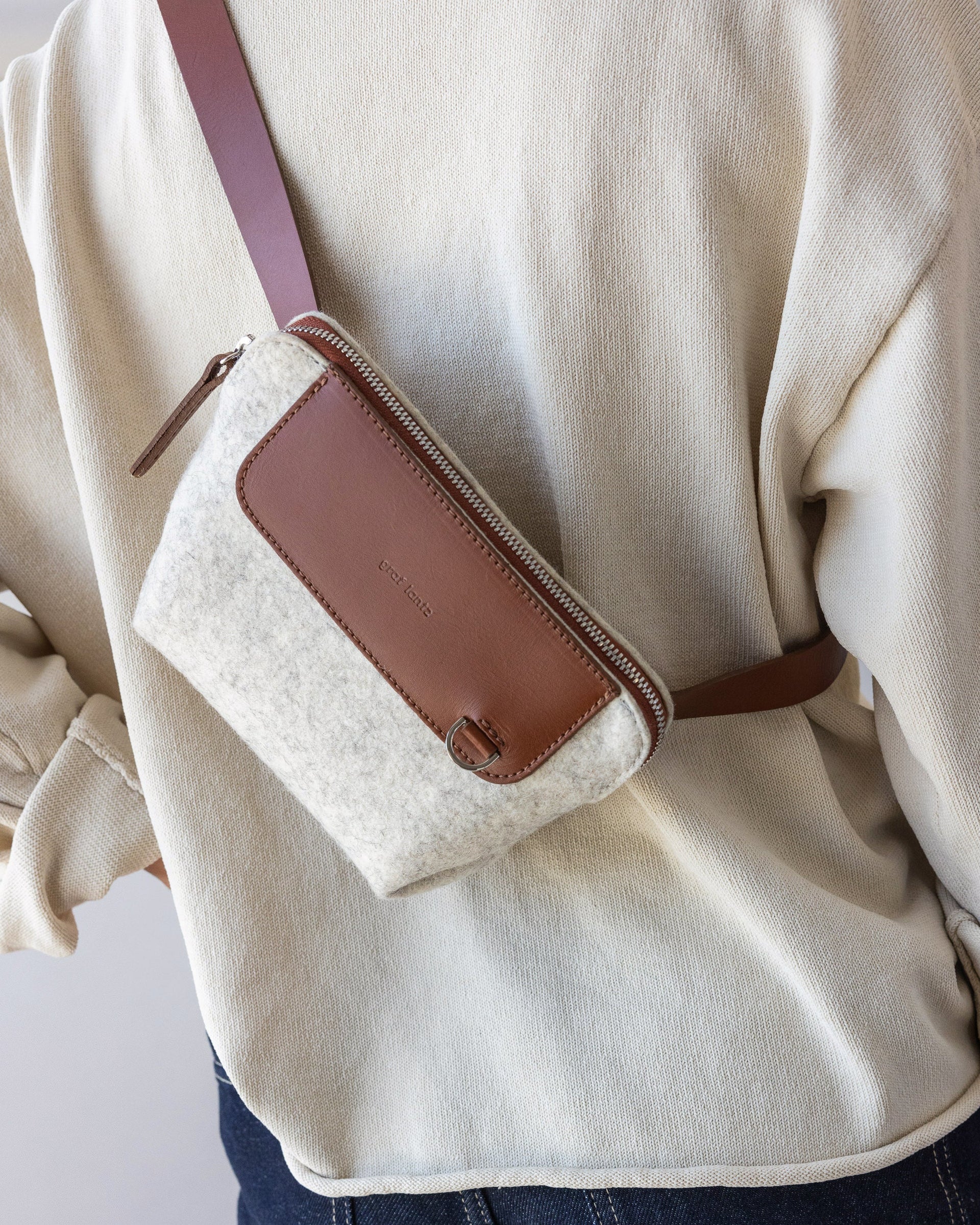 Rear view of a standing woman with white Bedford Merino Wool Belt Bag used as crossbody with brown leather strap