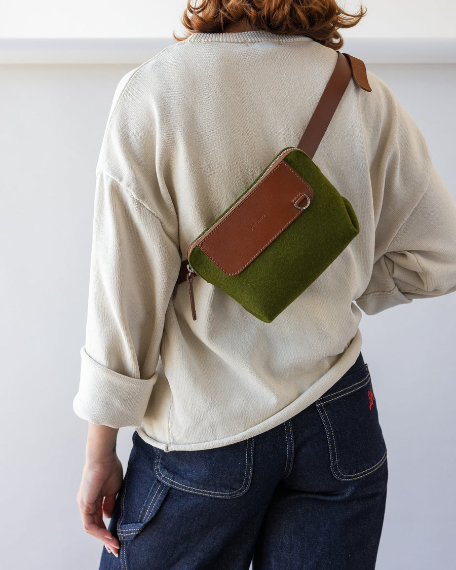 Rear view of a standing woman with green Bedford Merino Wool Belt Bag used as crossbody with brown leather strap