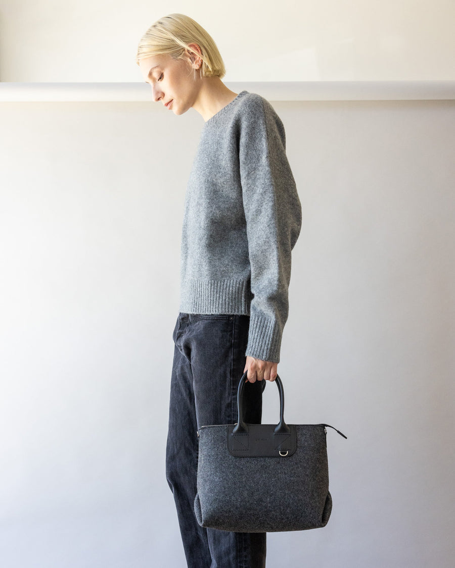 Standing woman holding charcoal Bedford Merino Wool Stachel on its handles with one hand by her side