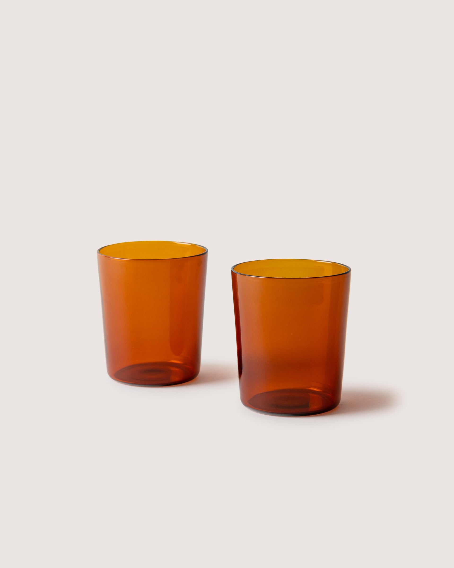 Two large Glas Tumbler in color burnt orange, white background