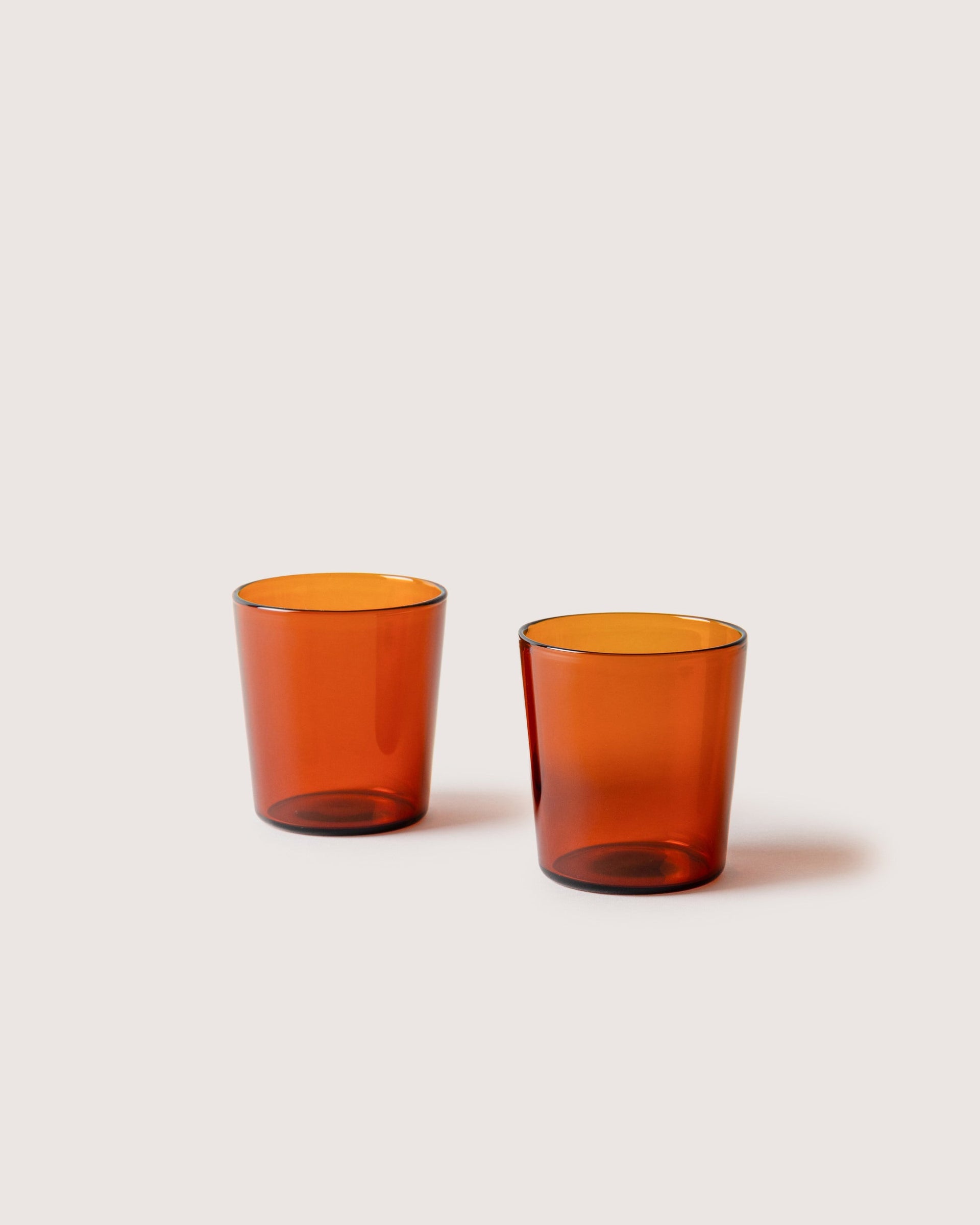 Two small Glas Tumbler in color Burnt Orange, white background