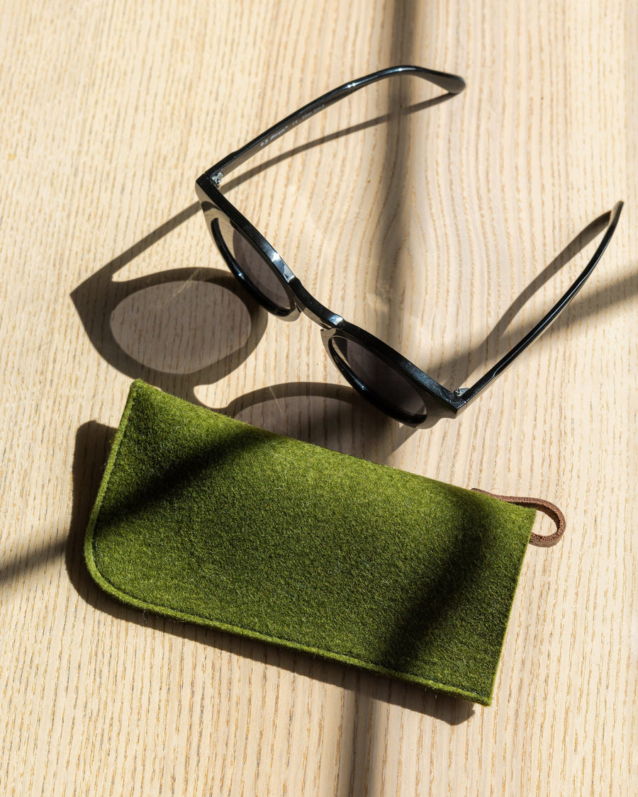 Green Classic Merino Wool Eyeglass Sleeve on a wooden tabletop next to black sunglasses