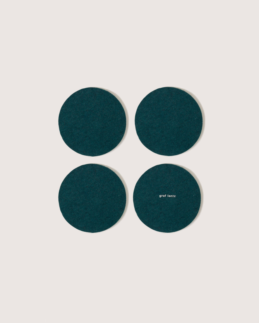 Four round coasters in color Kombu, white background