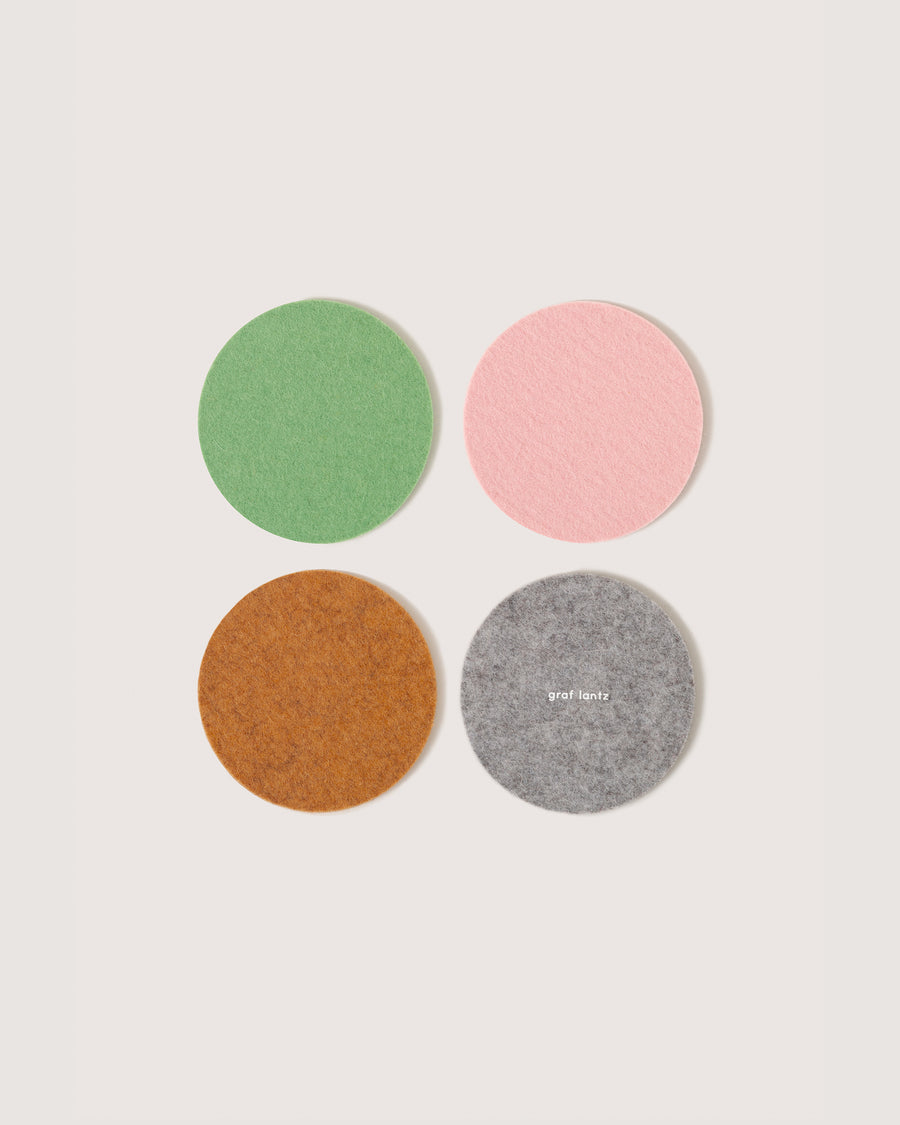 Four round felt coasters in Miso, Matcha, Rocksalt, and Granite colors, white background