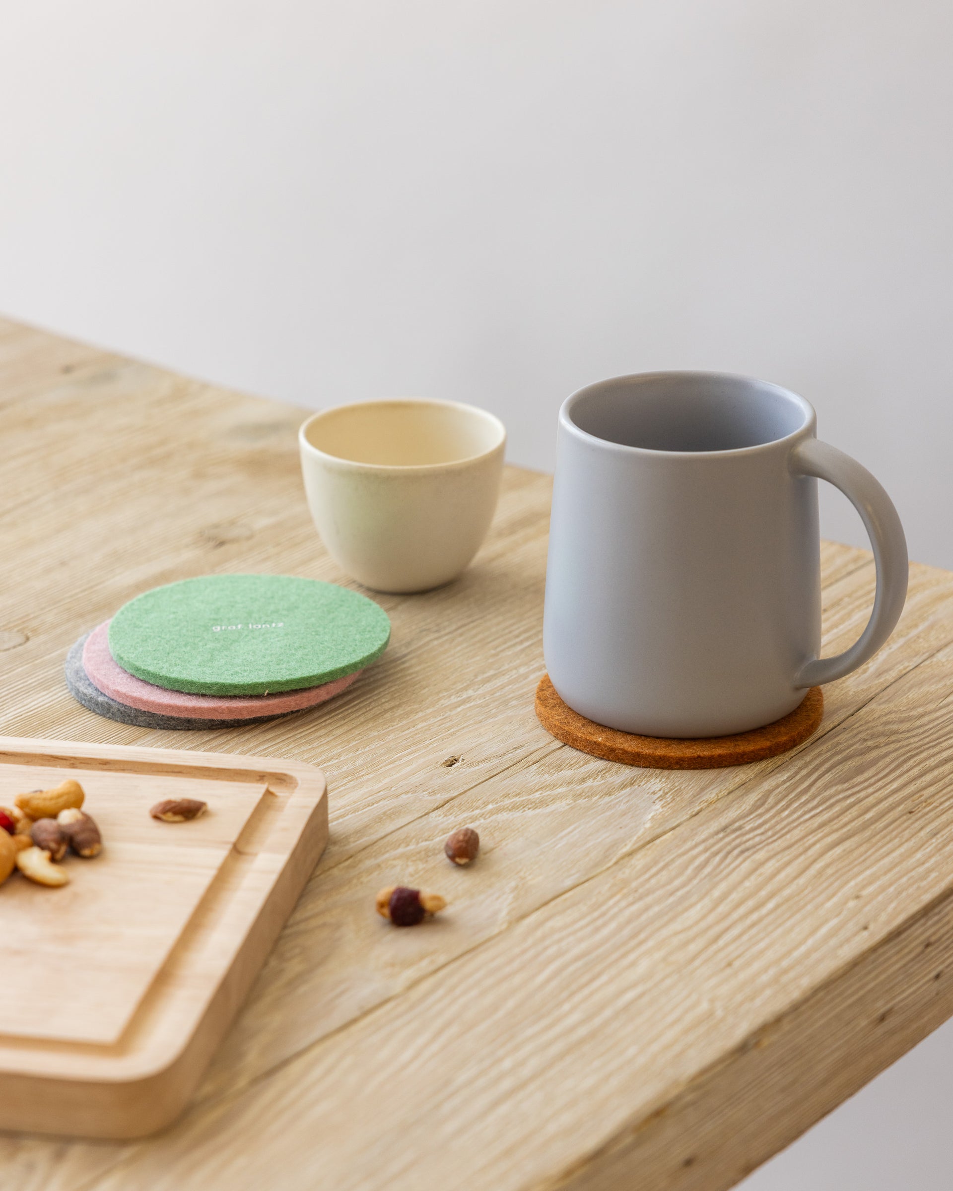 Stack of three round coasters, a white mug standing on a rust-colored coaster on a wooden tabletop