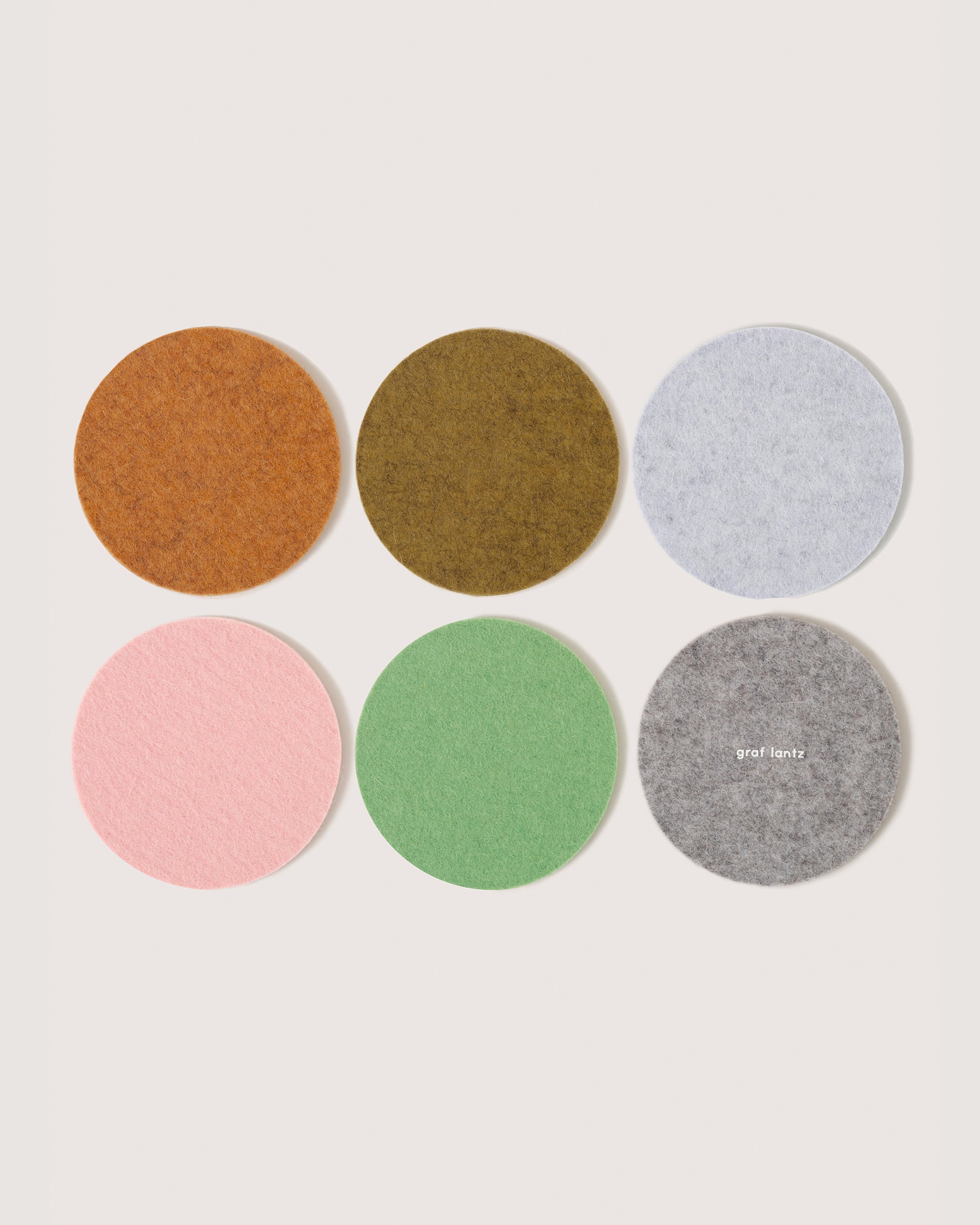Six round felt coasters in Miso, Matcha, Fog, Ochre, Rock Salt, and Granite colors by Graf Lantz, white background