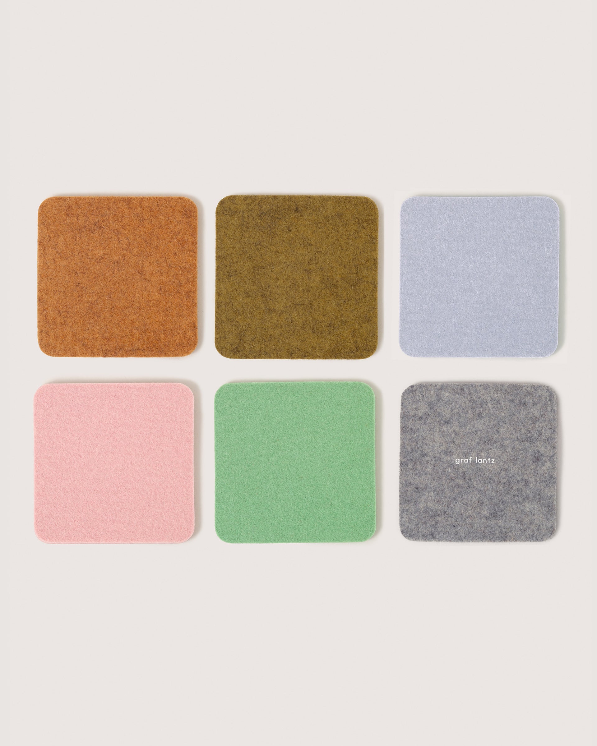 Six square felt coasters in Miso, Matcha, Fog, Ochre, Rock Salt, and Granite colors by Graf Lantz, white background