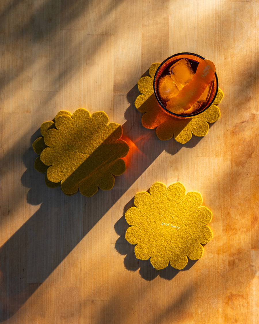 Hand-cut Merino Wool Felt Crest Coasters in dijon color in a decorative setting
