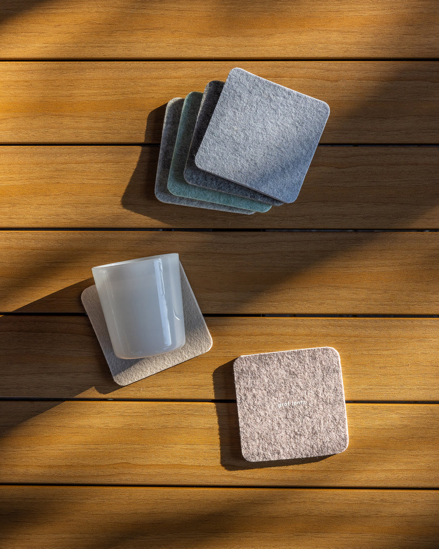 A stack of four dawn-colored Merino wool felt coasters while two more coasters lie below 
